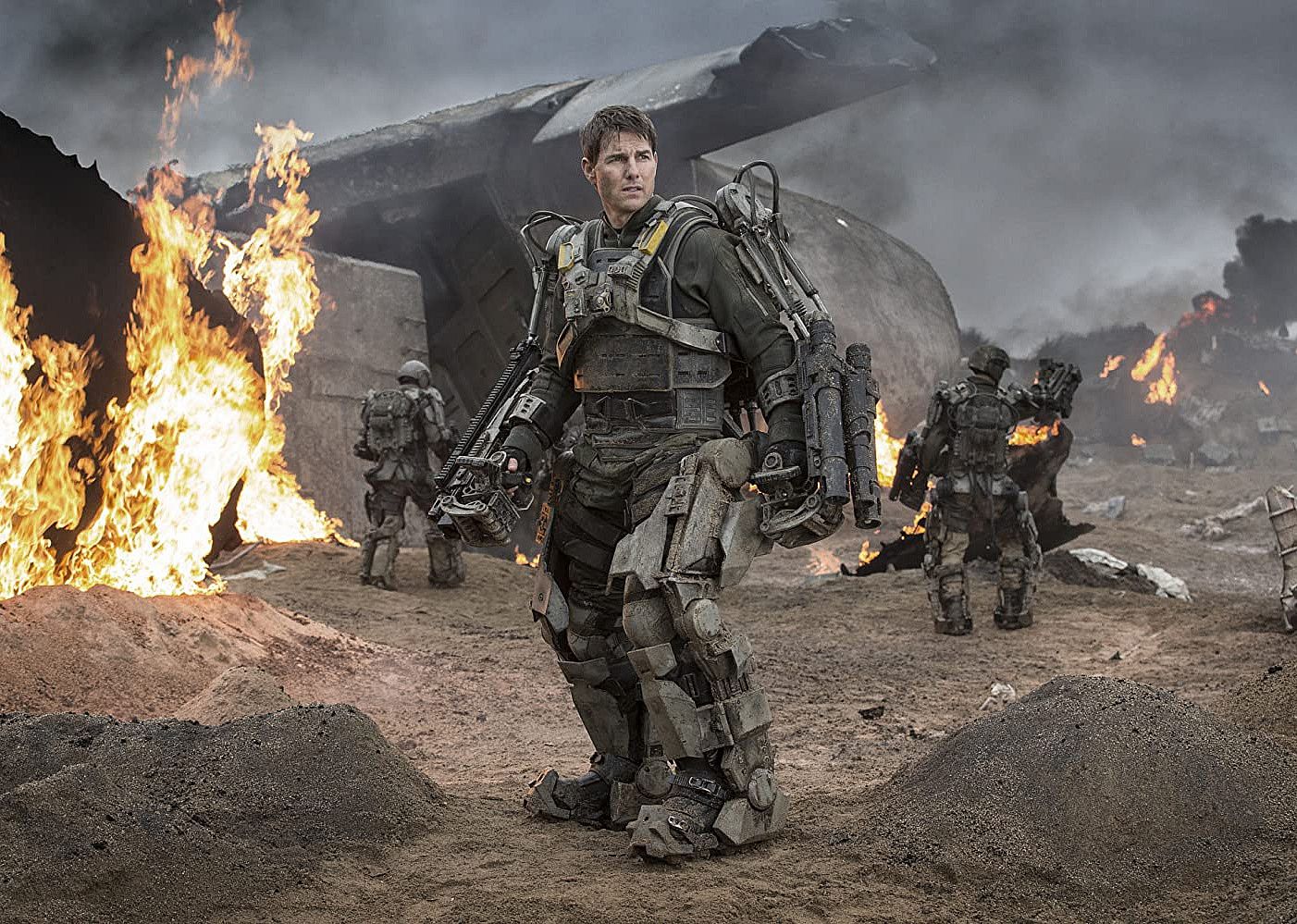 Tom Cruise in heavy armor in battle with fires around him.