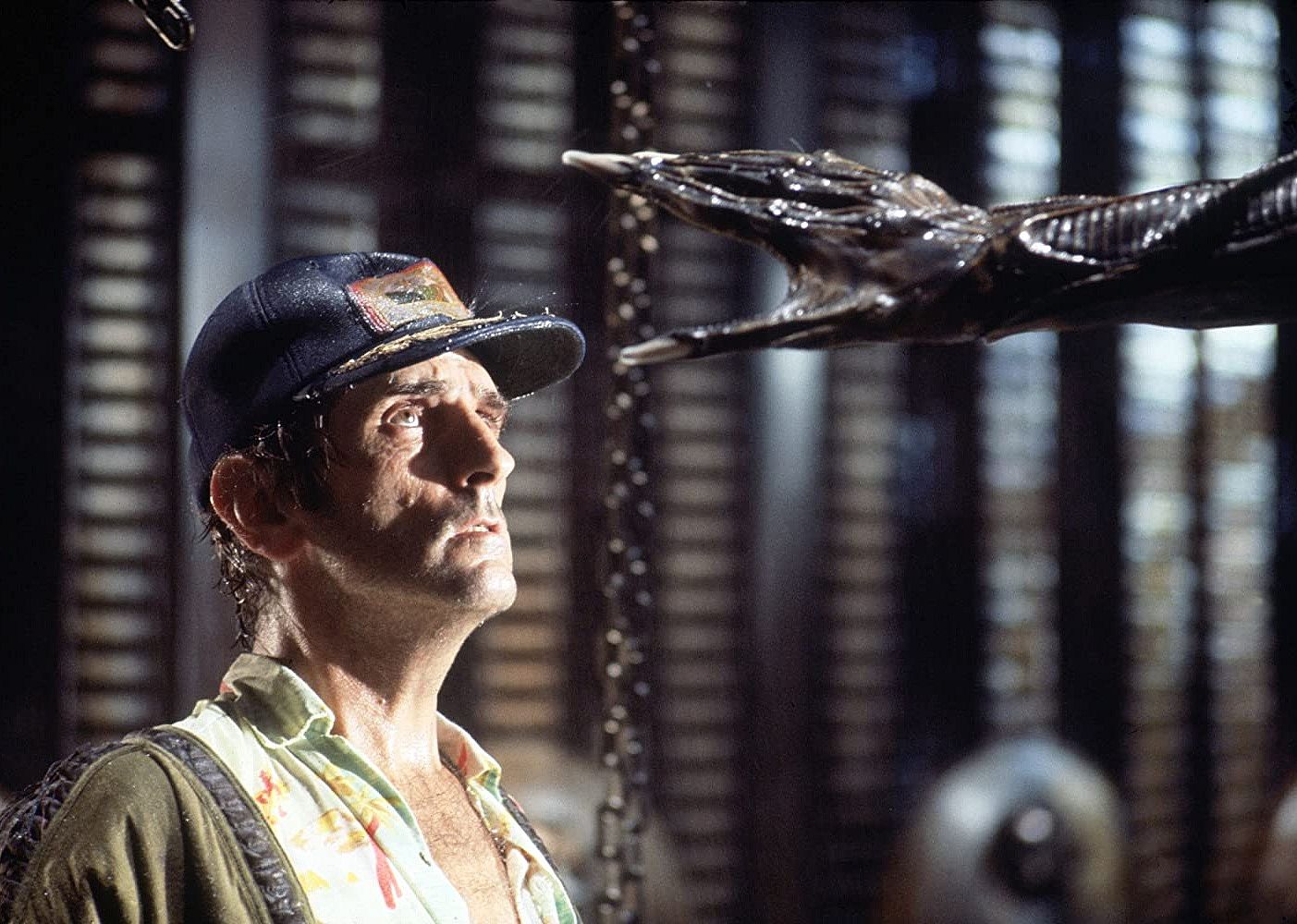 Harry Dean Stanton looking up at a large black creature's hand.