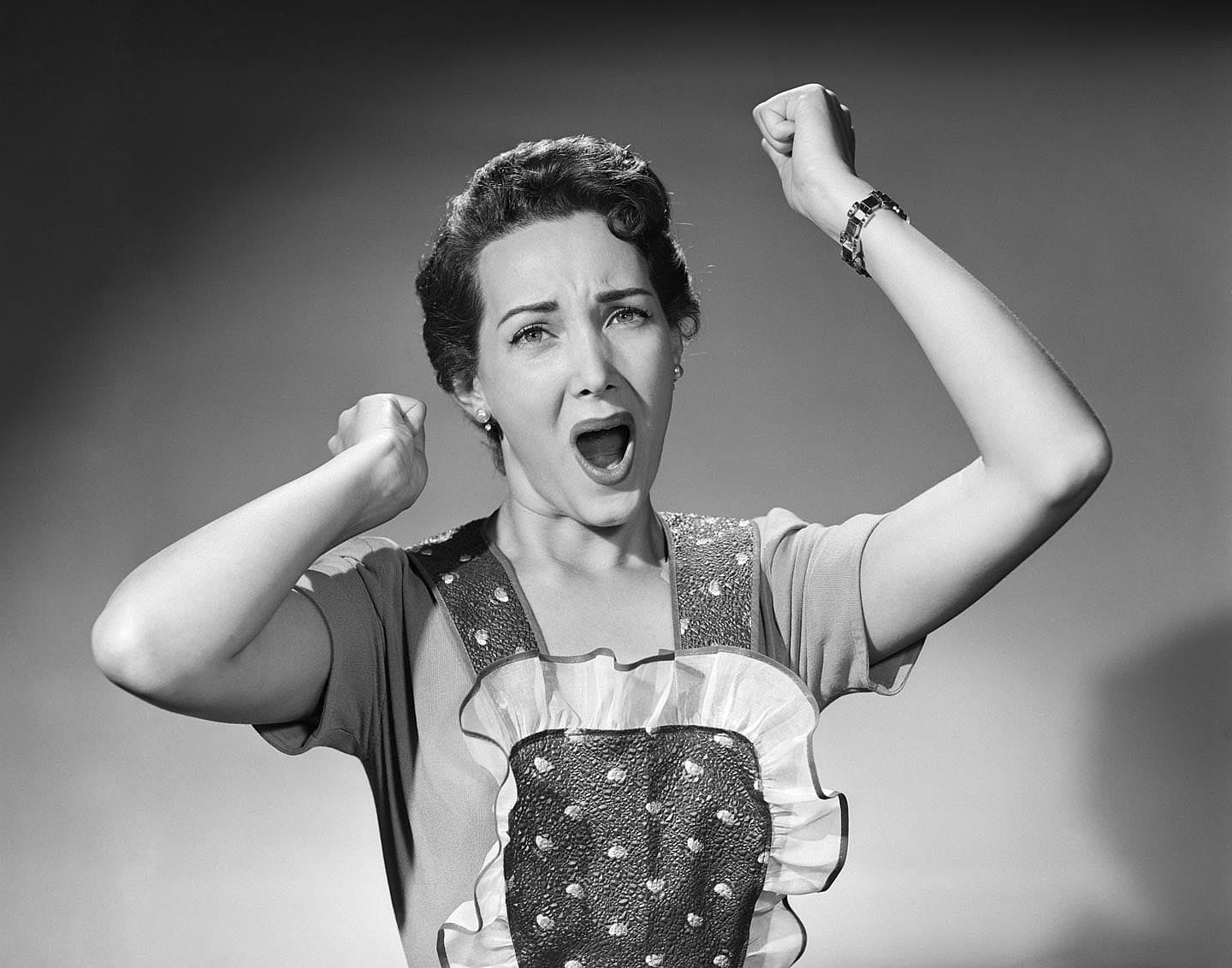 Woman in the 1950s wearing an apron raising her hands in frustration