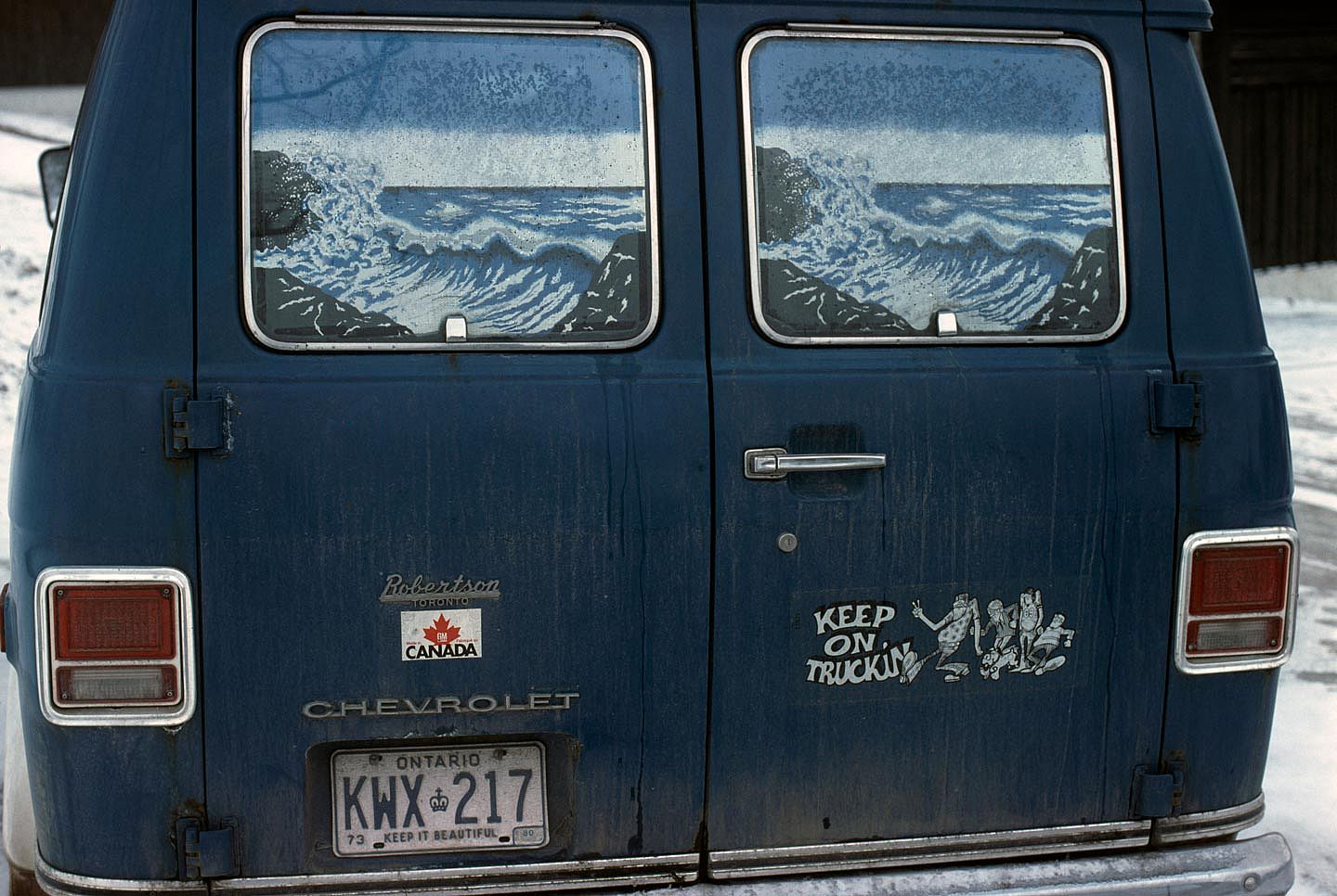 Vintage photo of a blue van with a 'Keep on Truckin' sticker