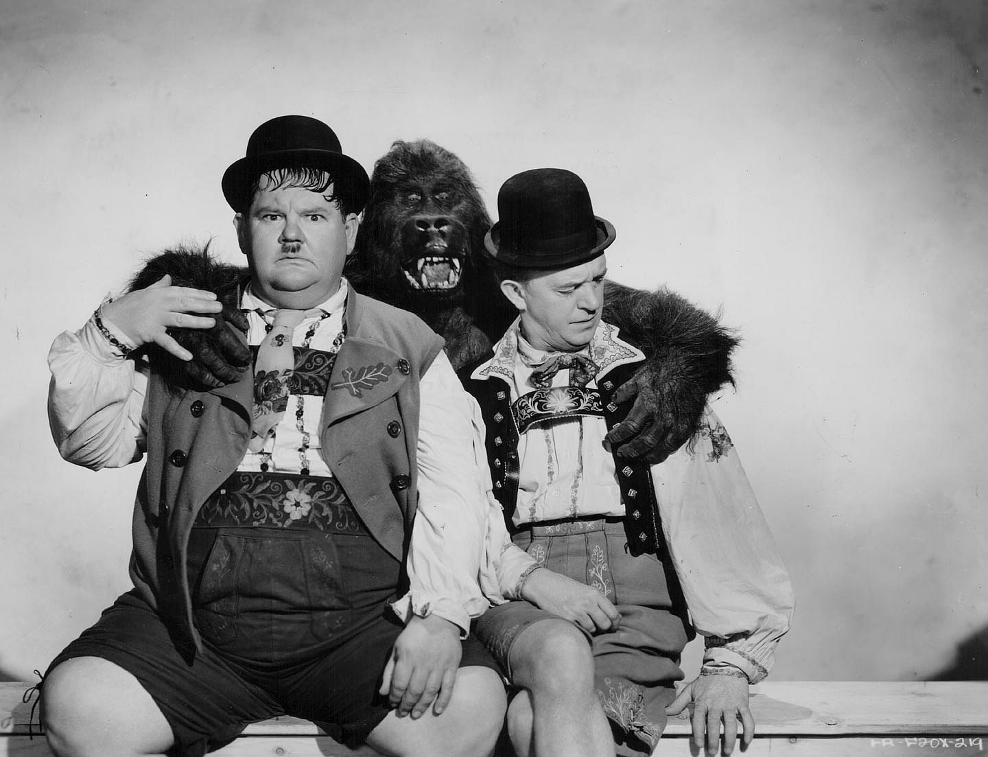 Comedy double act Oliver Hardy and Stan Laurel, posing with a man in a gorilla suit in a promotional portrait for the movie 'Swiss Miss', 1938.