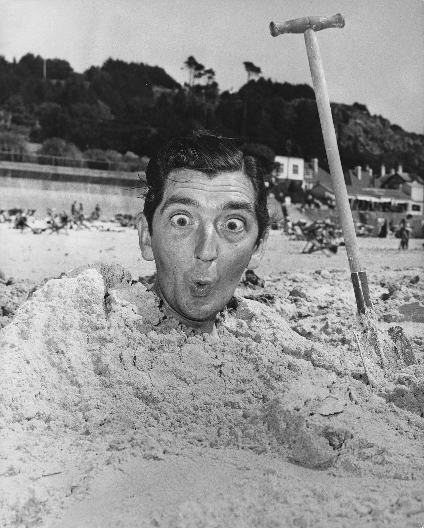 British comic actor Ted Lune (1920 - 1968) of television's 'The Army Game' buried up to his neck in sand whilst on holiday in Jersey, July 1960. 