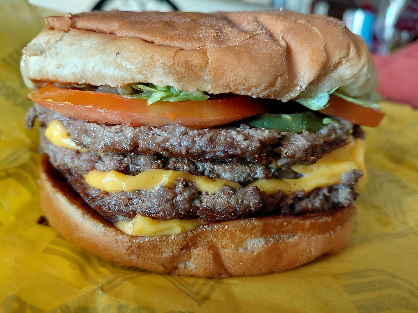 A photo of a Whataburger Triple Meat cheeseburger sitting on a wrapper