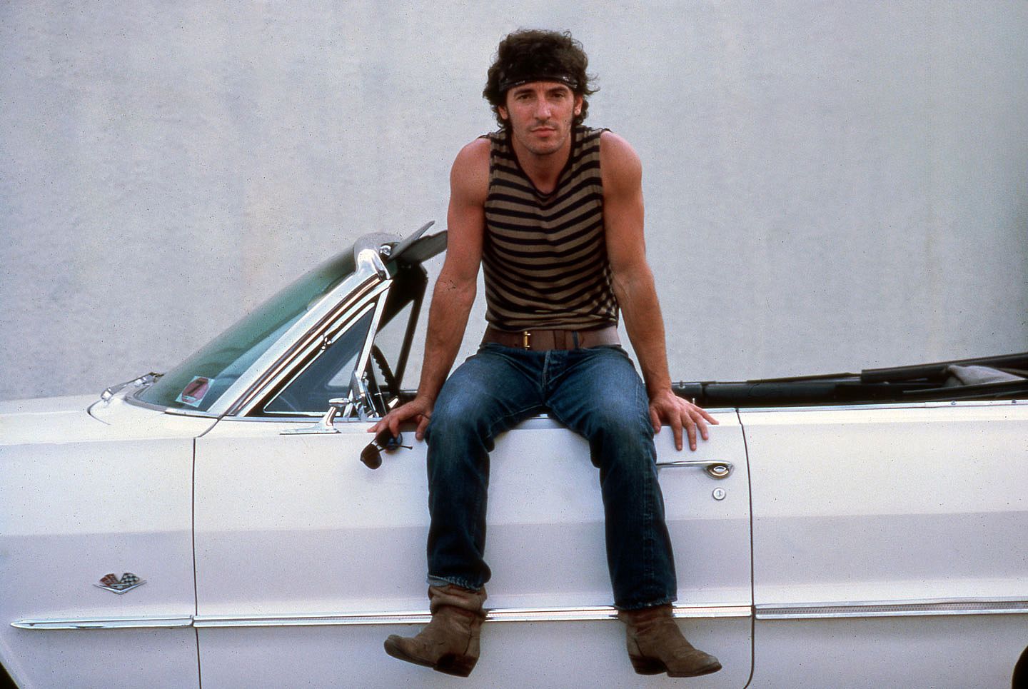 Bruce Springsteen poses on the drivers side door of a white convertible for a portrait in 1984.