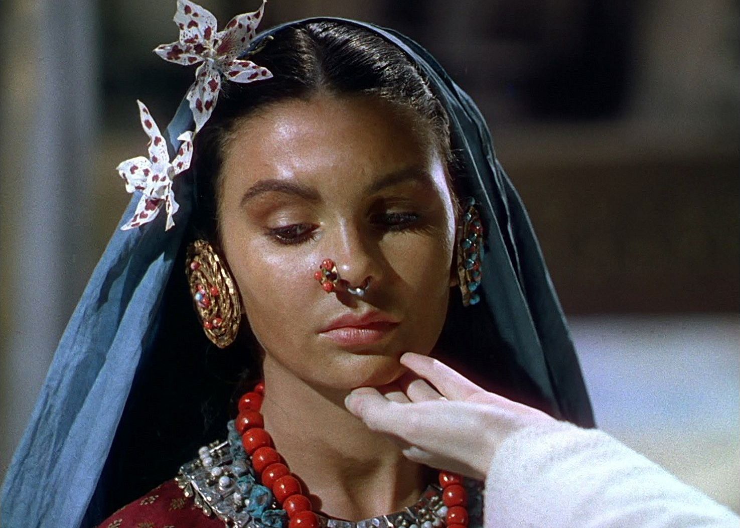 A young woman in a head scarf with large round earrings and a nose ring.