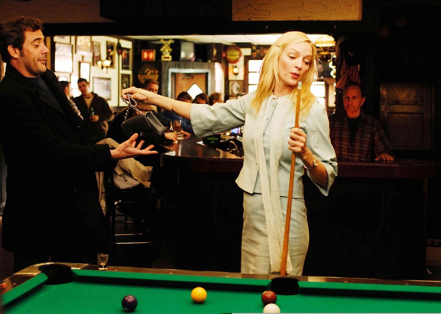Uma Thurman handing Jeffrey Dean Morgan her purse at a pool table.