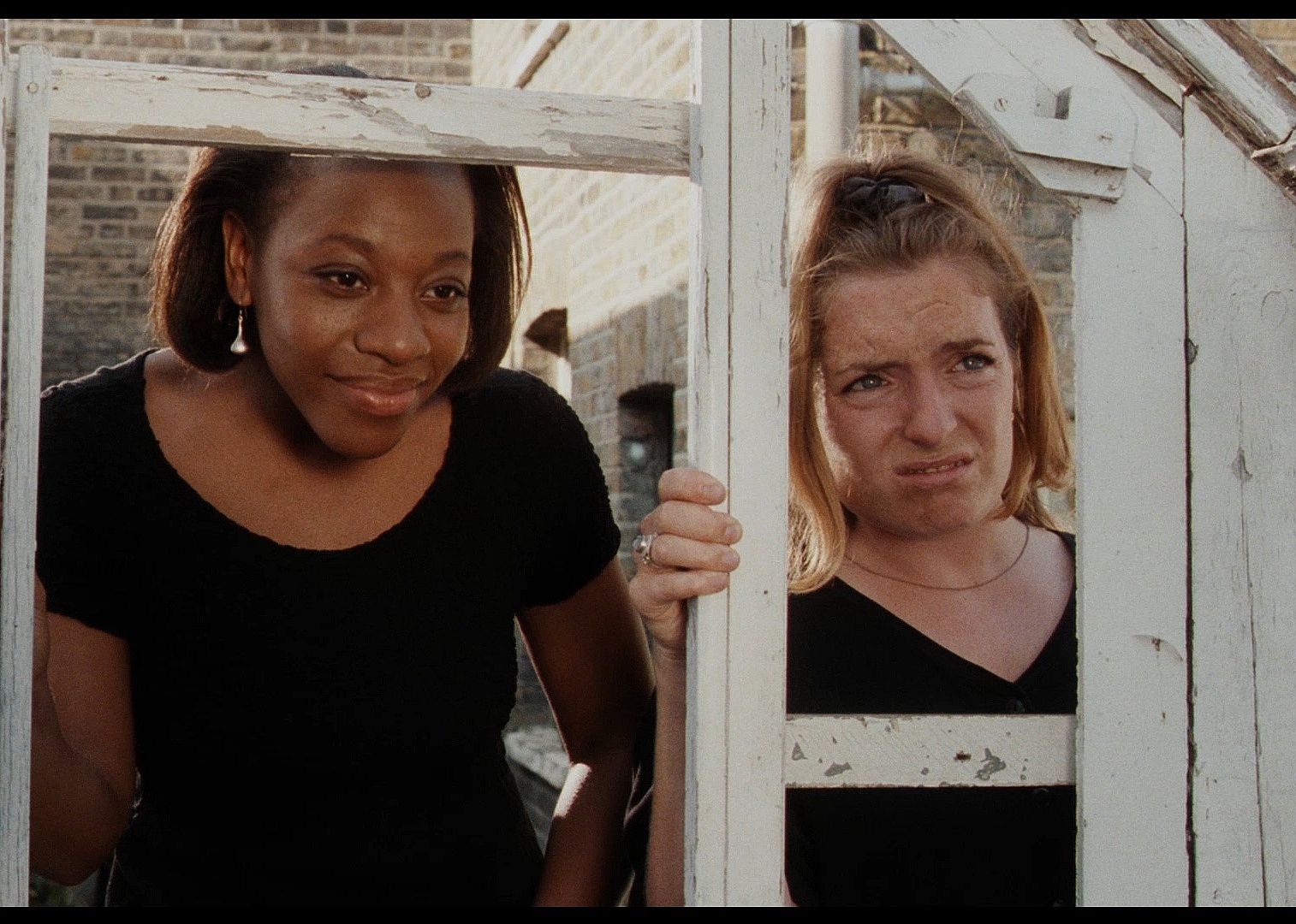 Two women look through an old dilapidated sructure outside.