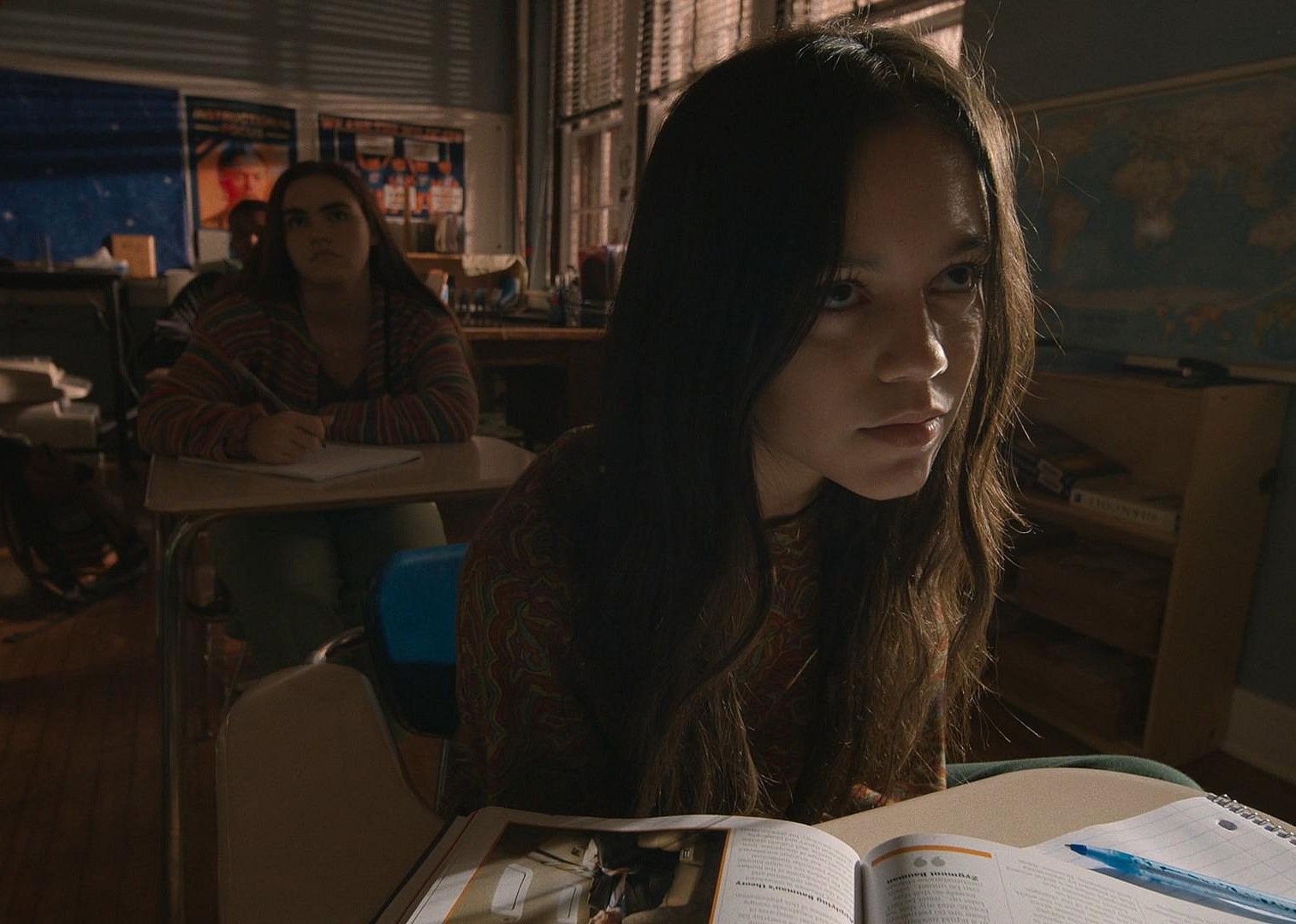 A girl looking annoyed in a classroom.