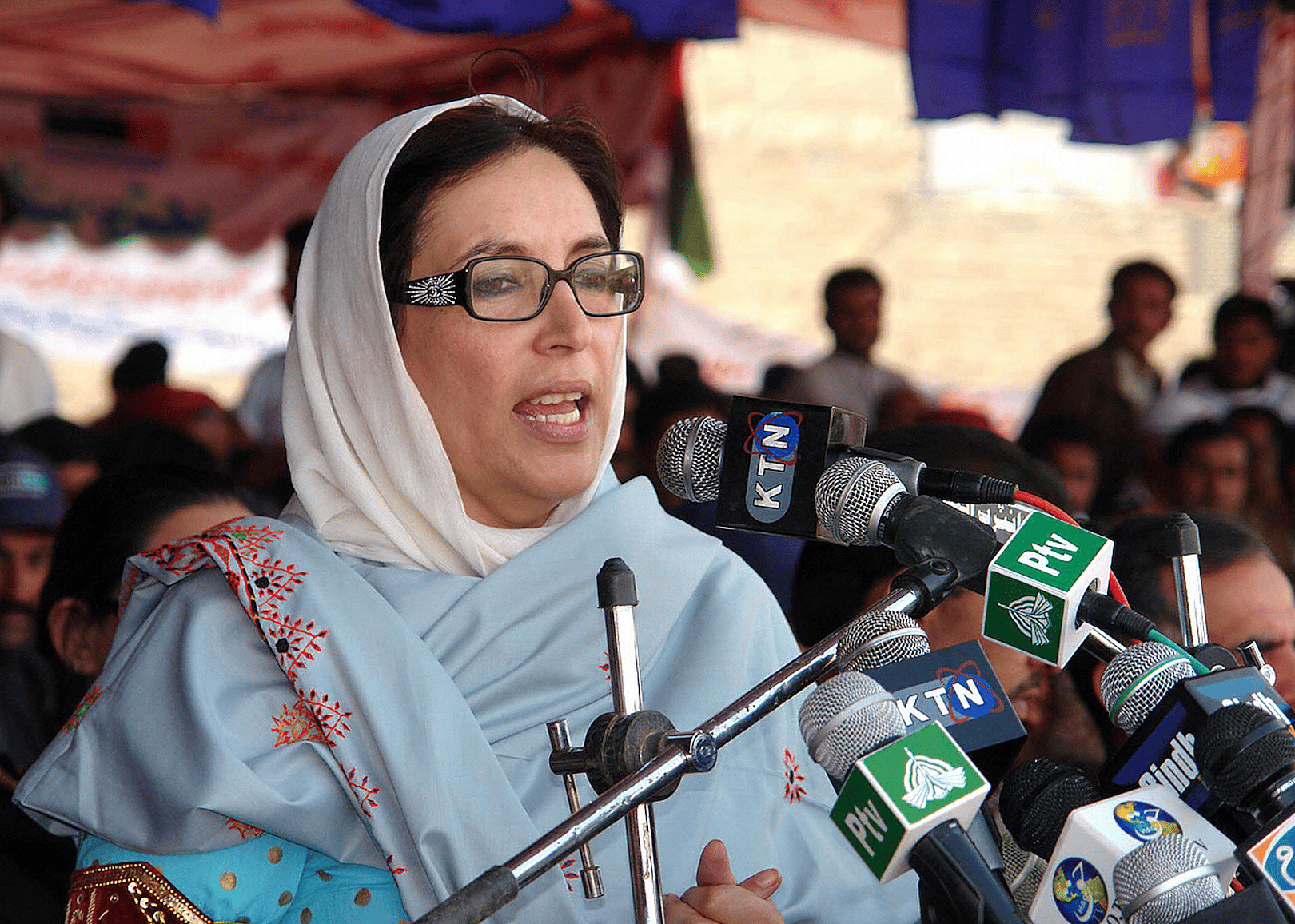 Benazir Bhutto talking into press microphones.