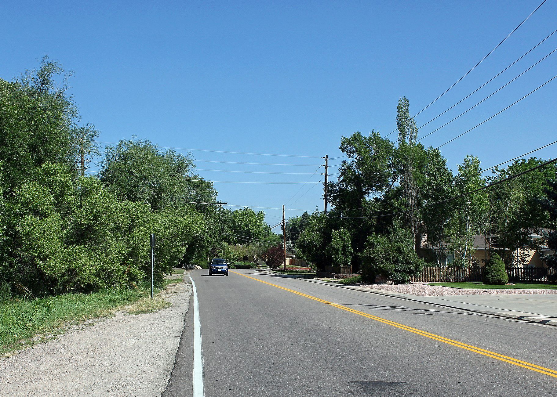 A highway lined with trees on one side and homes on the other.