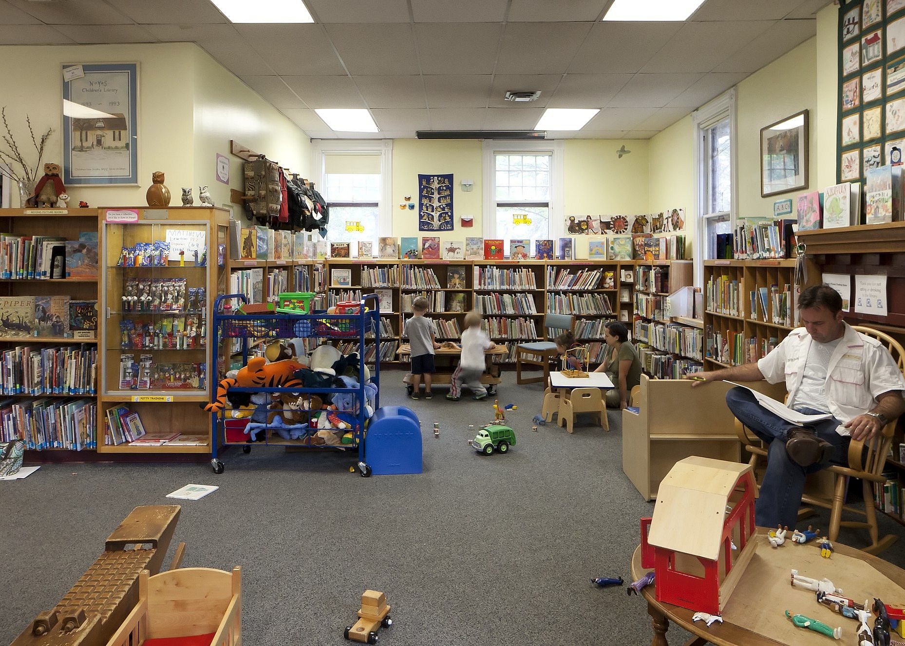 People reading and kids playing in a library.