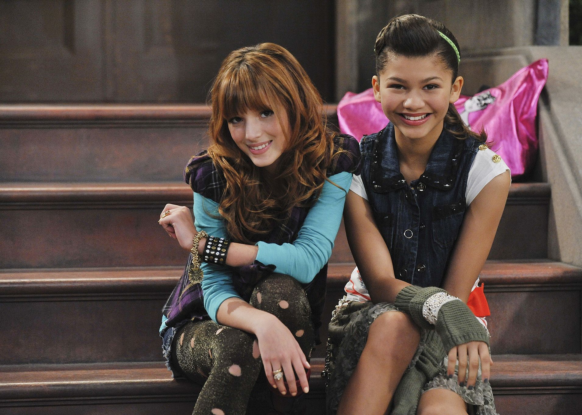 Two young girls sit together smiling and posing on some steps.