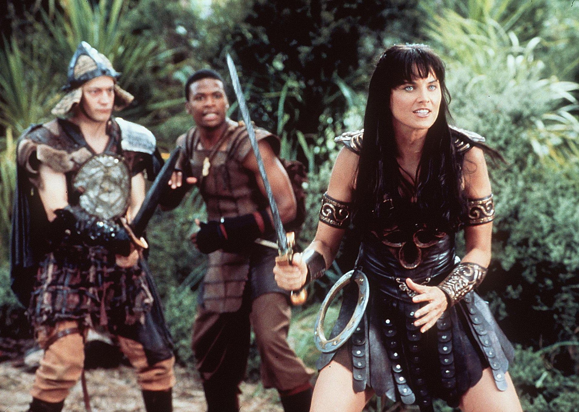 Lucy Lawless as Xena and other warriors engaged in battle with swords.