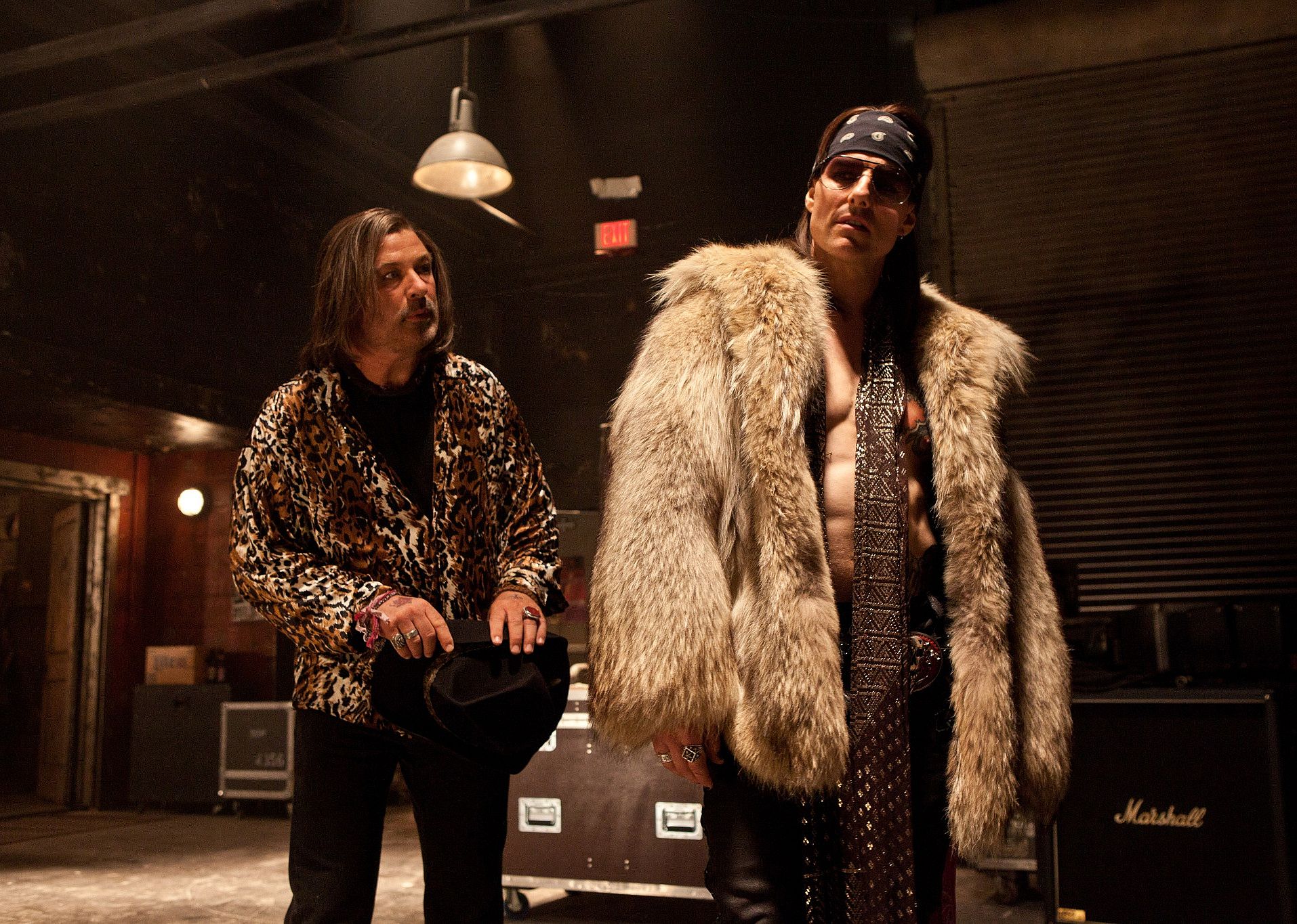 Tom Cruise, in a white fur coat, stands next to Alec Baldwin, wearing an animal print jacket.