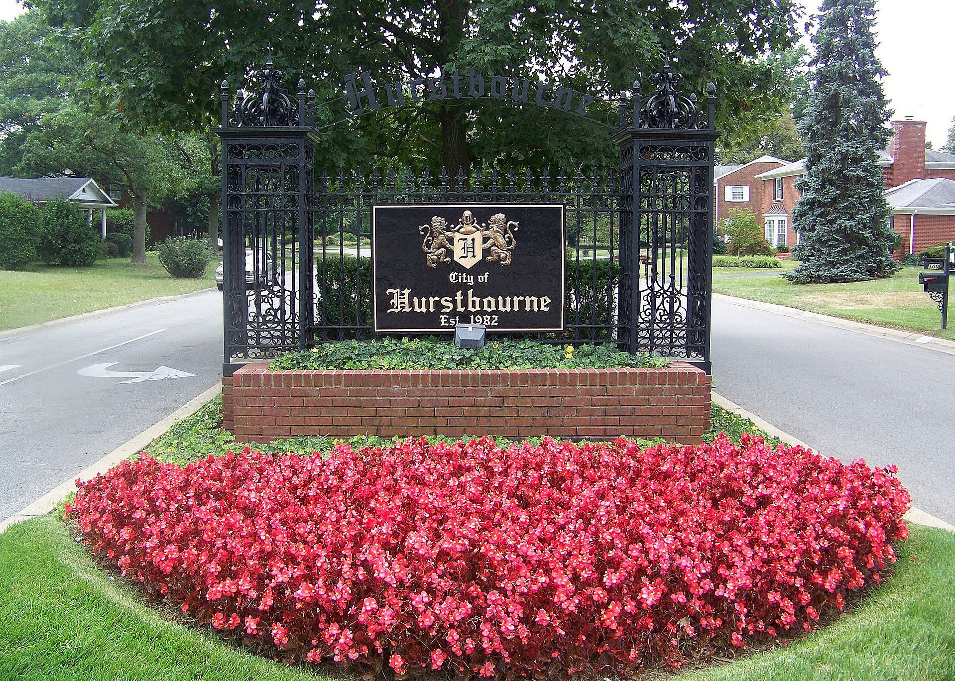 An iron entrance into Hurstbourne with pink flowers in the front.