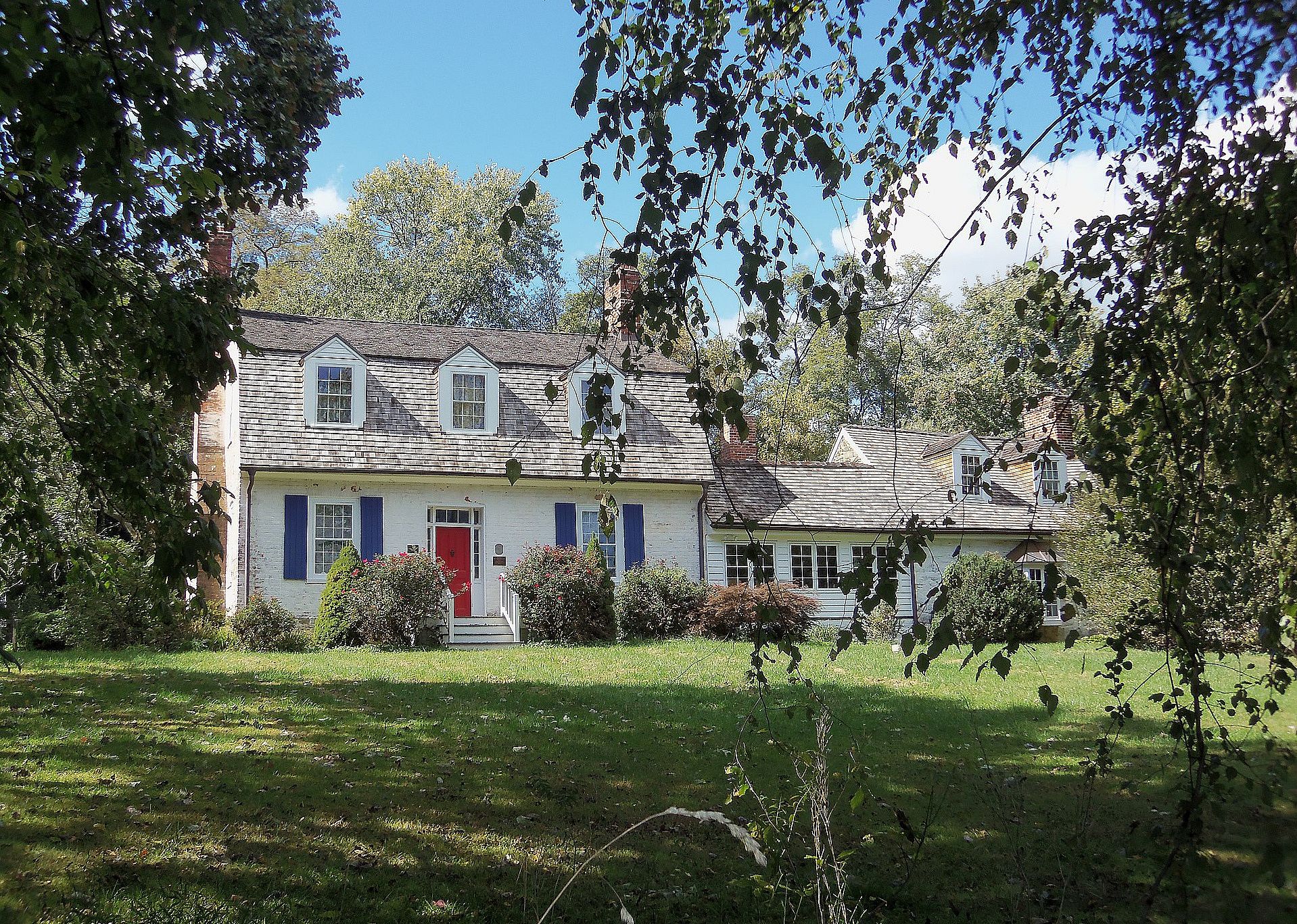 A white brick house with blue trim and a red door.