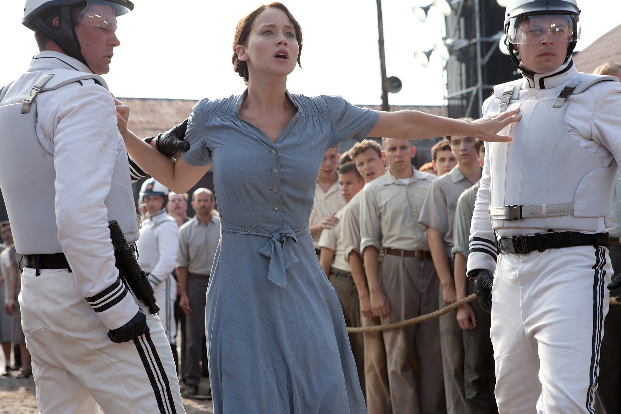 Jennifer Lawrence's Katniss Everdeen between two guards in white.