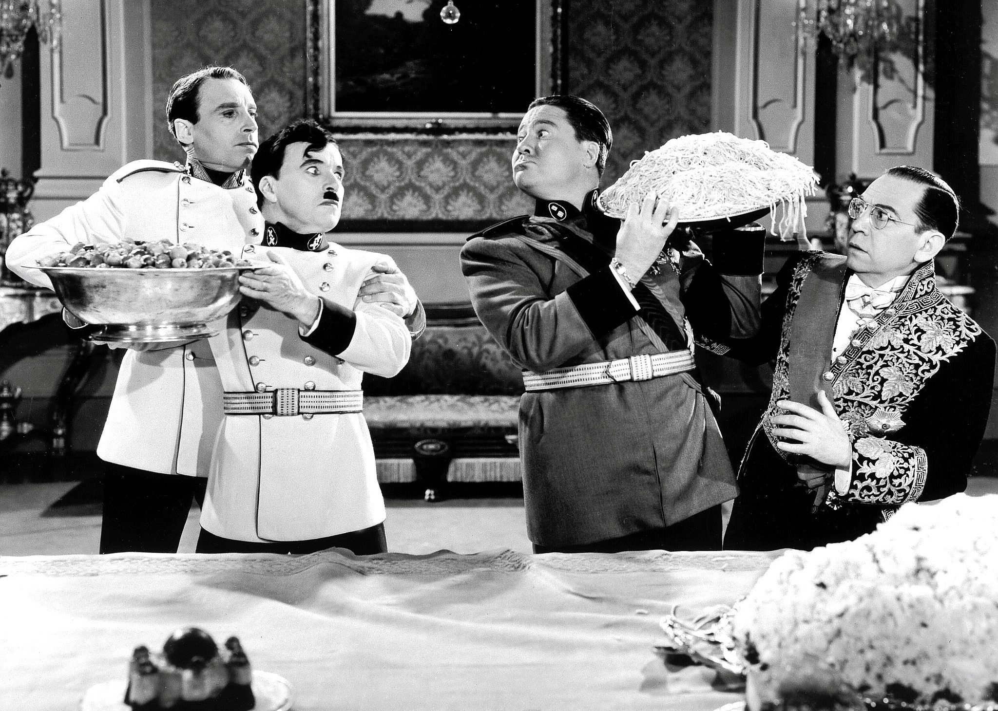 Two different dictators (one being Charles Chaplin) hold foods from their respective countries in big bowls pointed at each other.