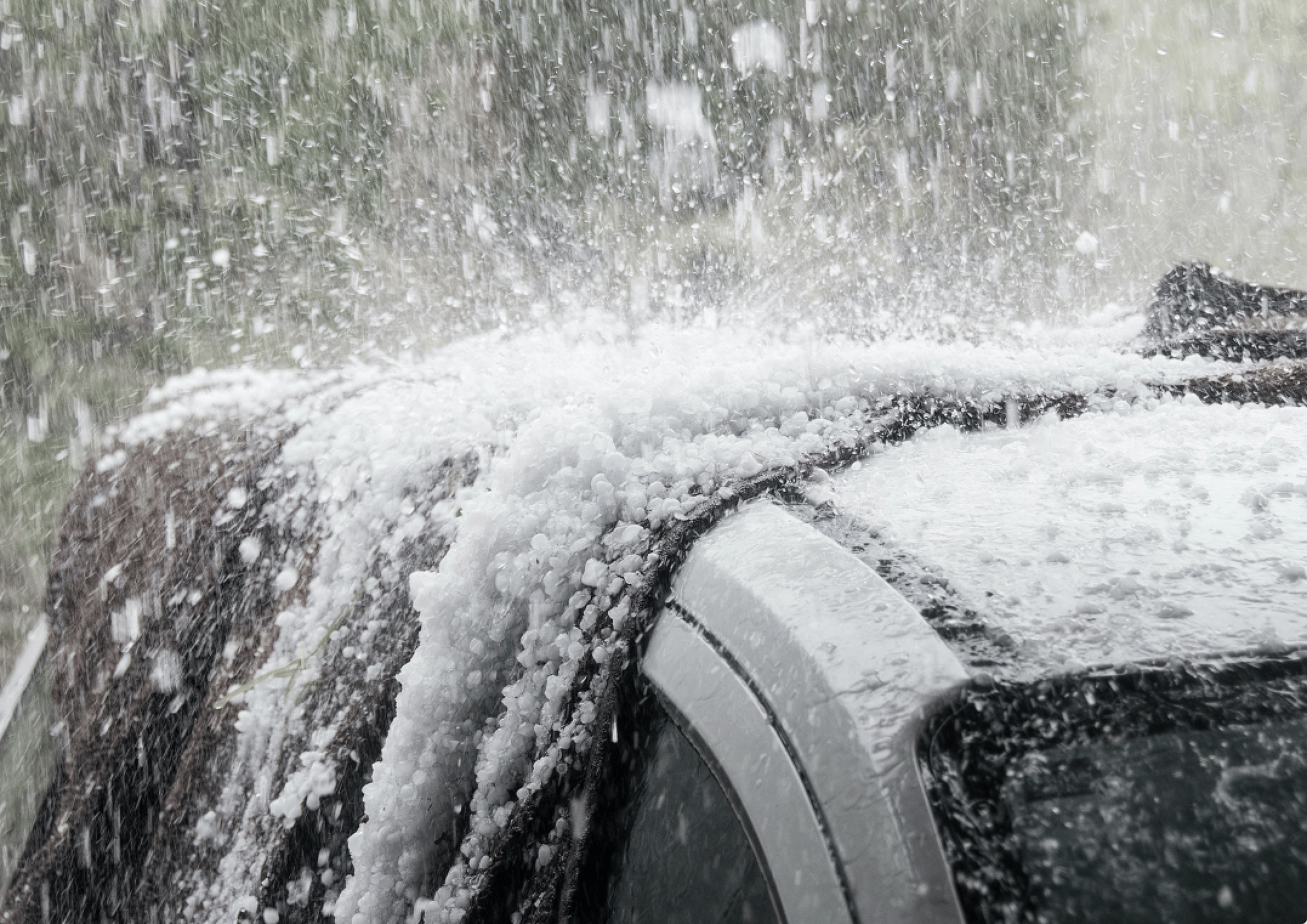 Hail crashes down onto the top of a car. 