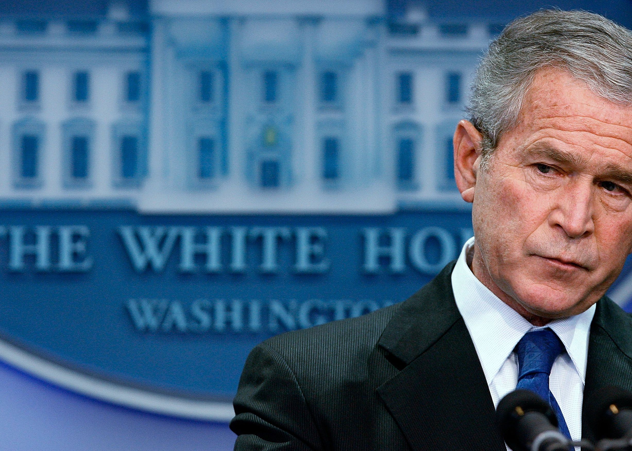 George W. Bush in front of the blue White House sign.