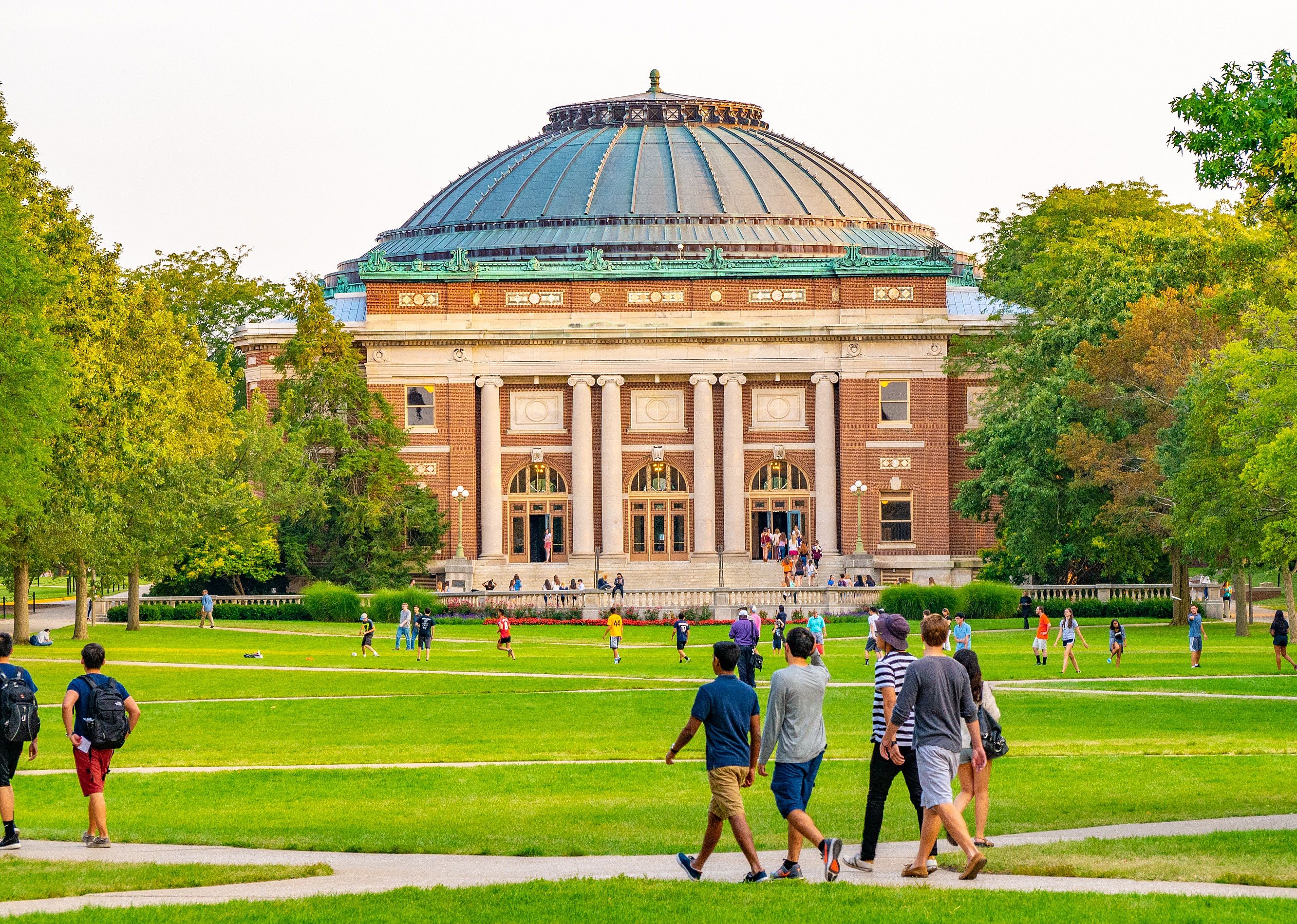 Students walk outdoors on lawn of the campus quad of Urbana Champaign.