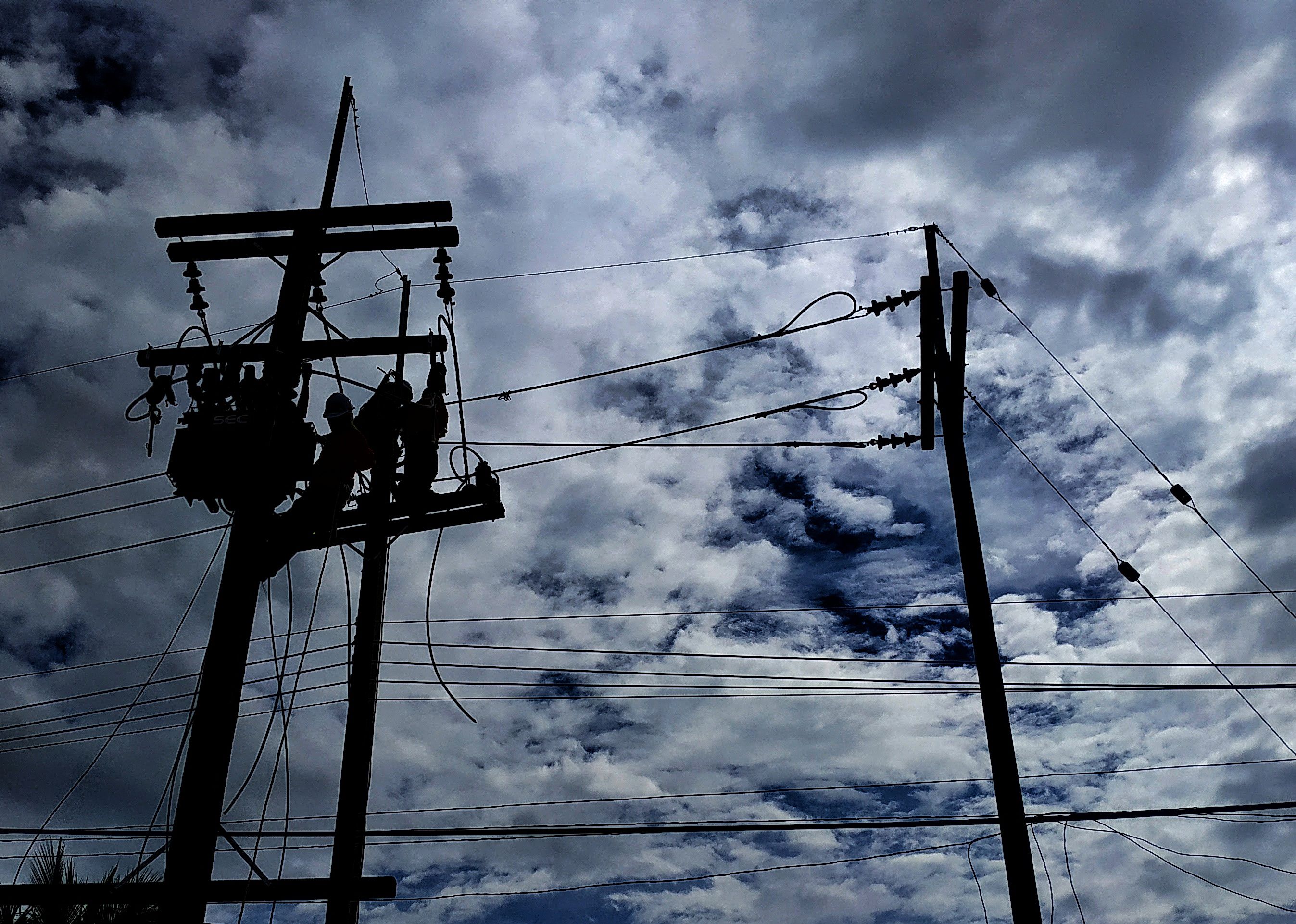 Electrician works on electric poles.