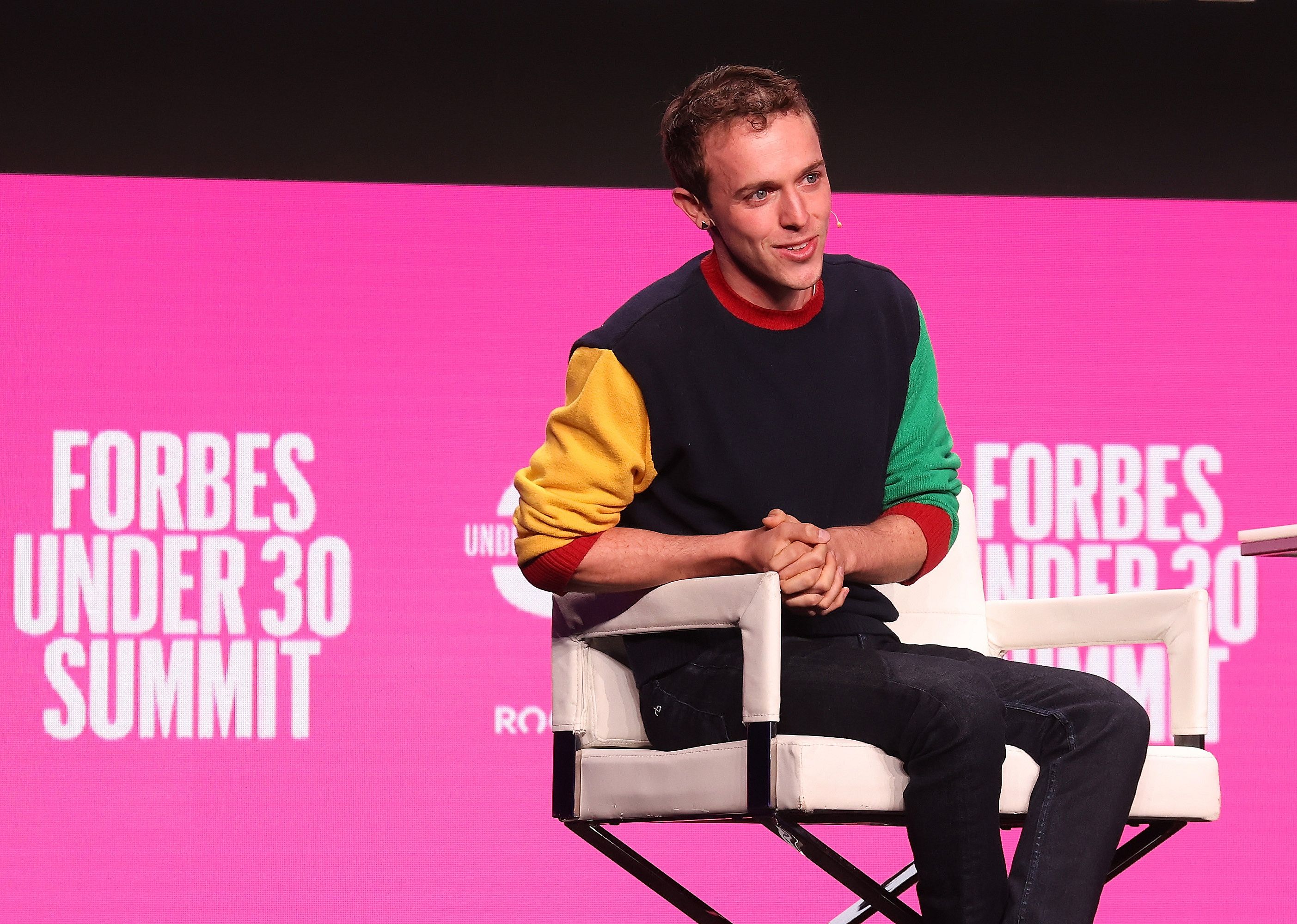 Ryan Breslow onstage in front of a pink background.