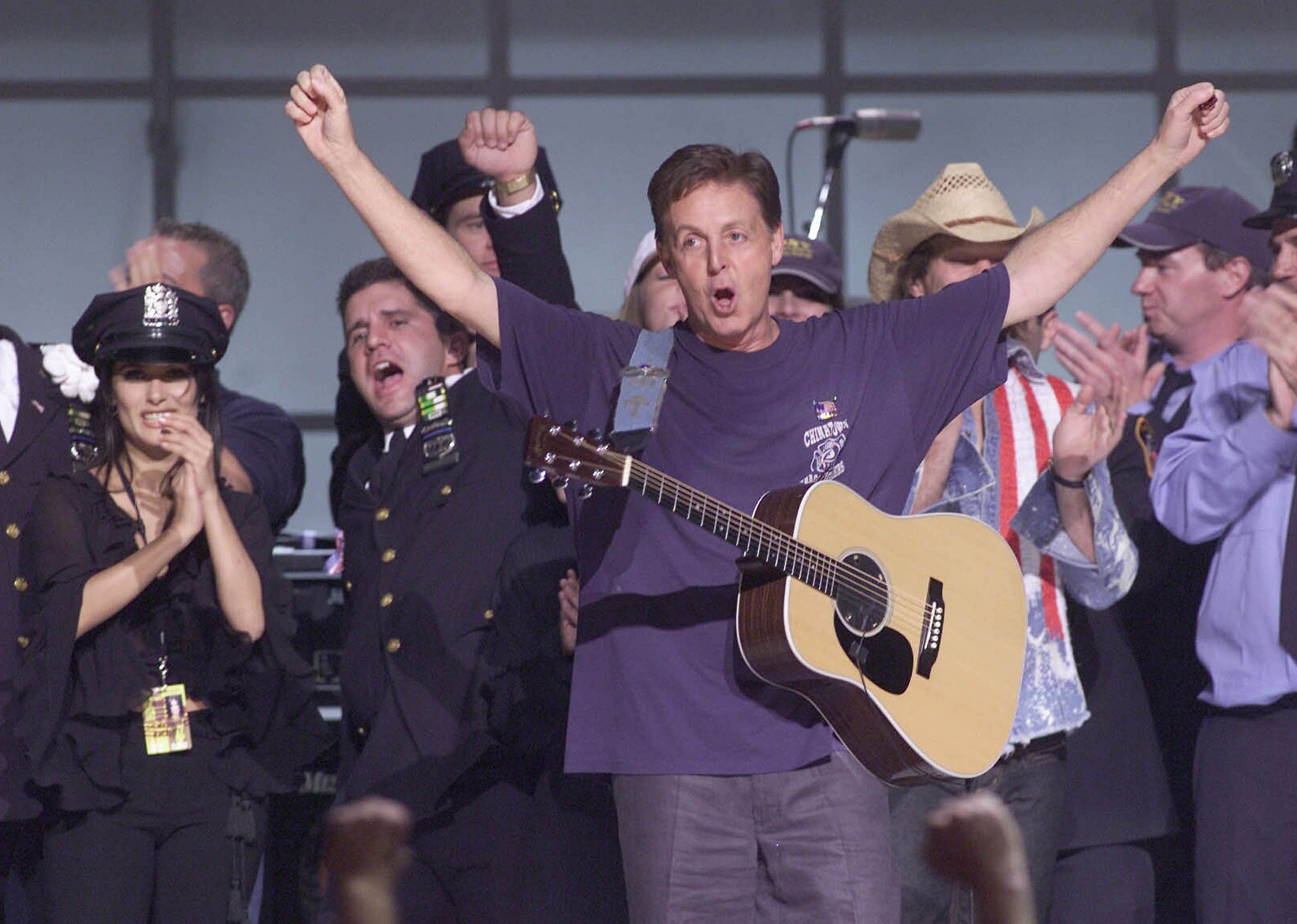 Paul McCartney performs on stage alongside other artists at The Concert for New York City.