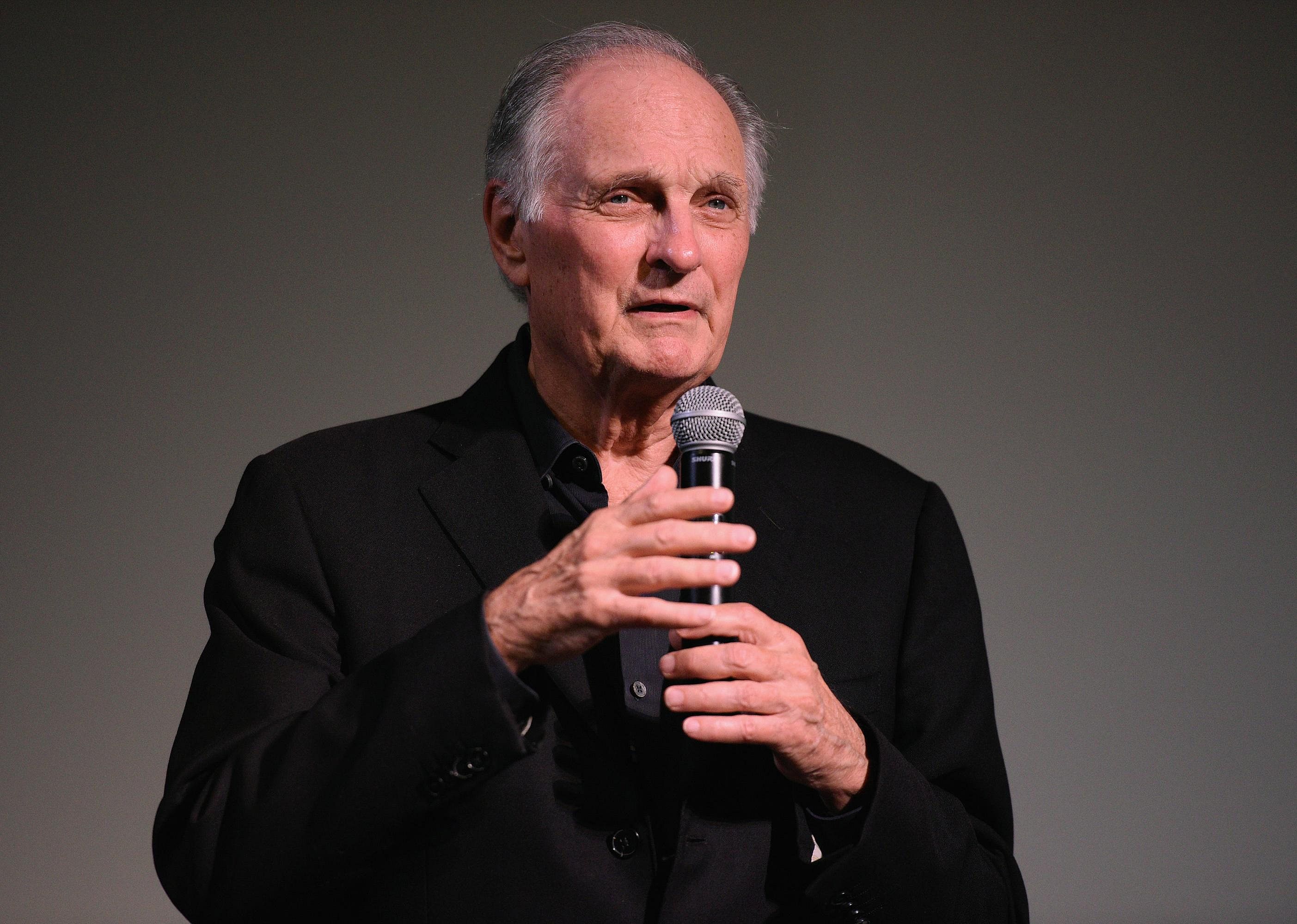 Alan Alda speaking into a mic. 