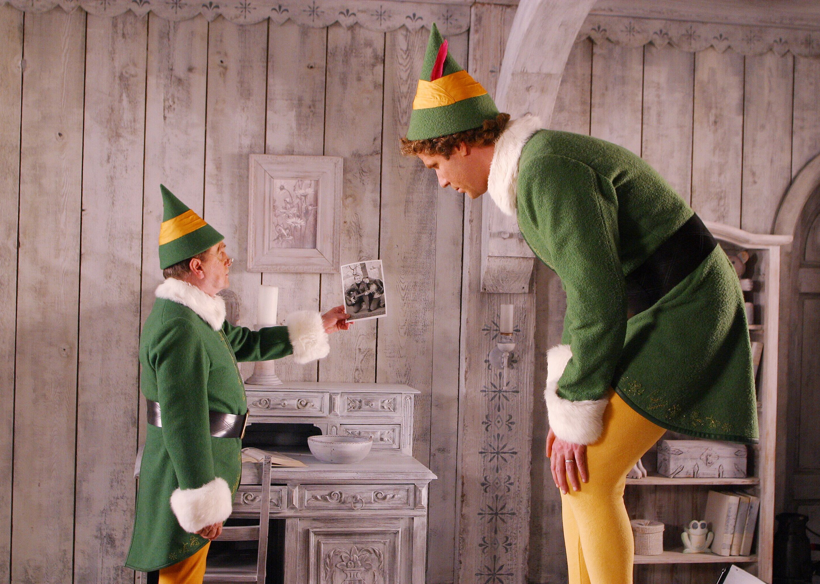 Bob Newhart, as a small elf, holding up a picture to Will Ferrell, who is considerably larger.