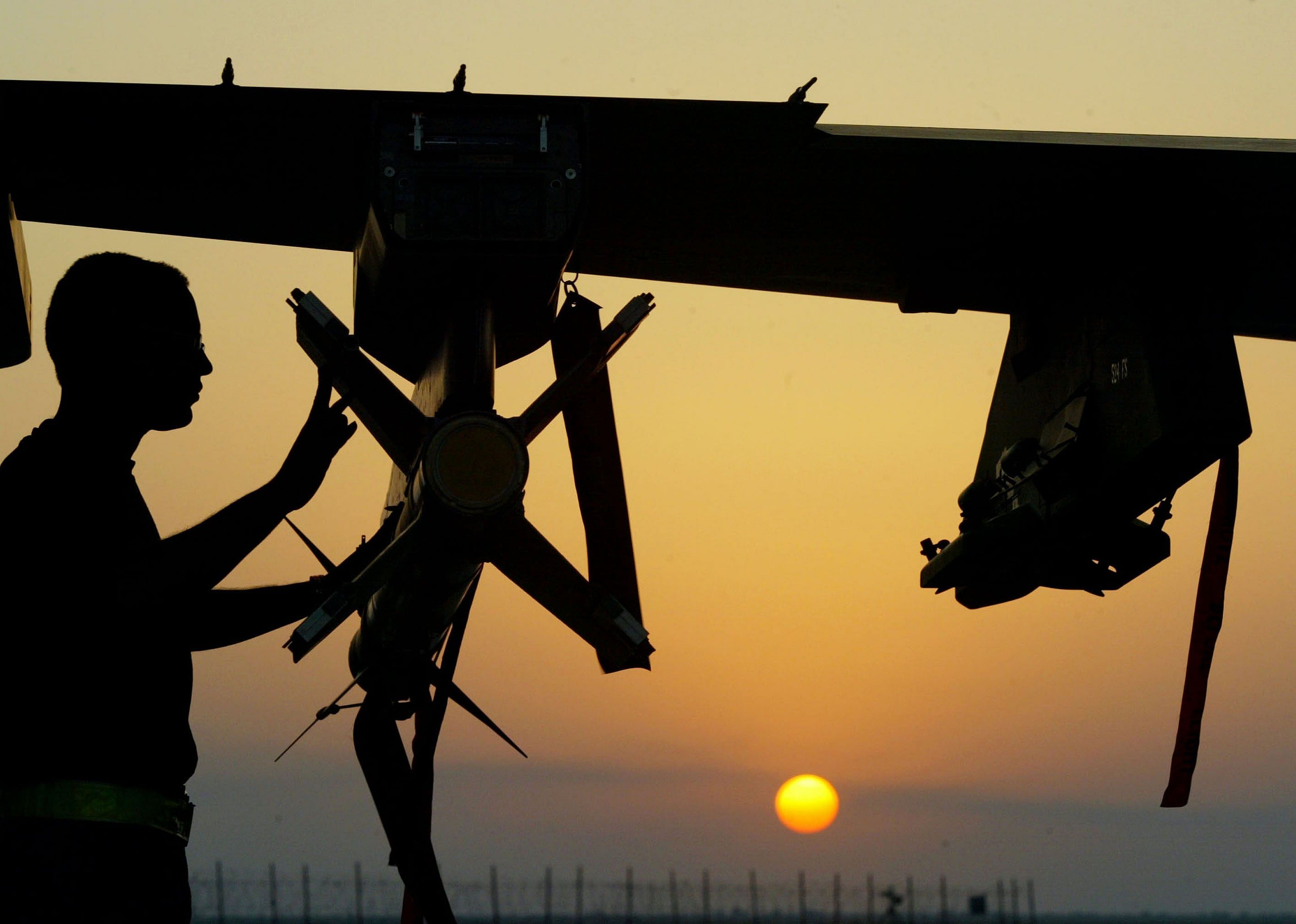 An Air Force pilot performs a post flight inspection on an F-16 Fighting Falcon at sunset at an airbase in the Gulf.