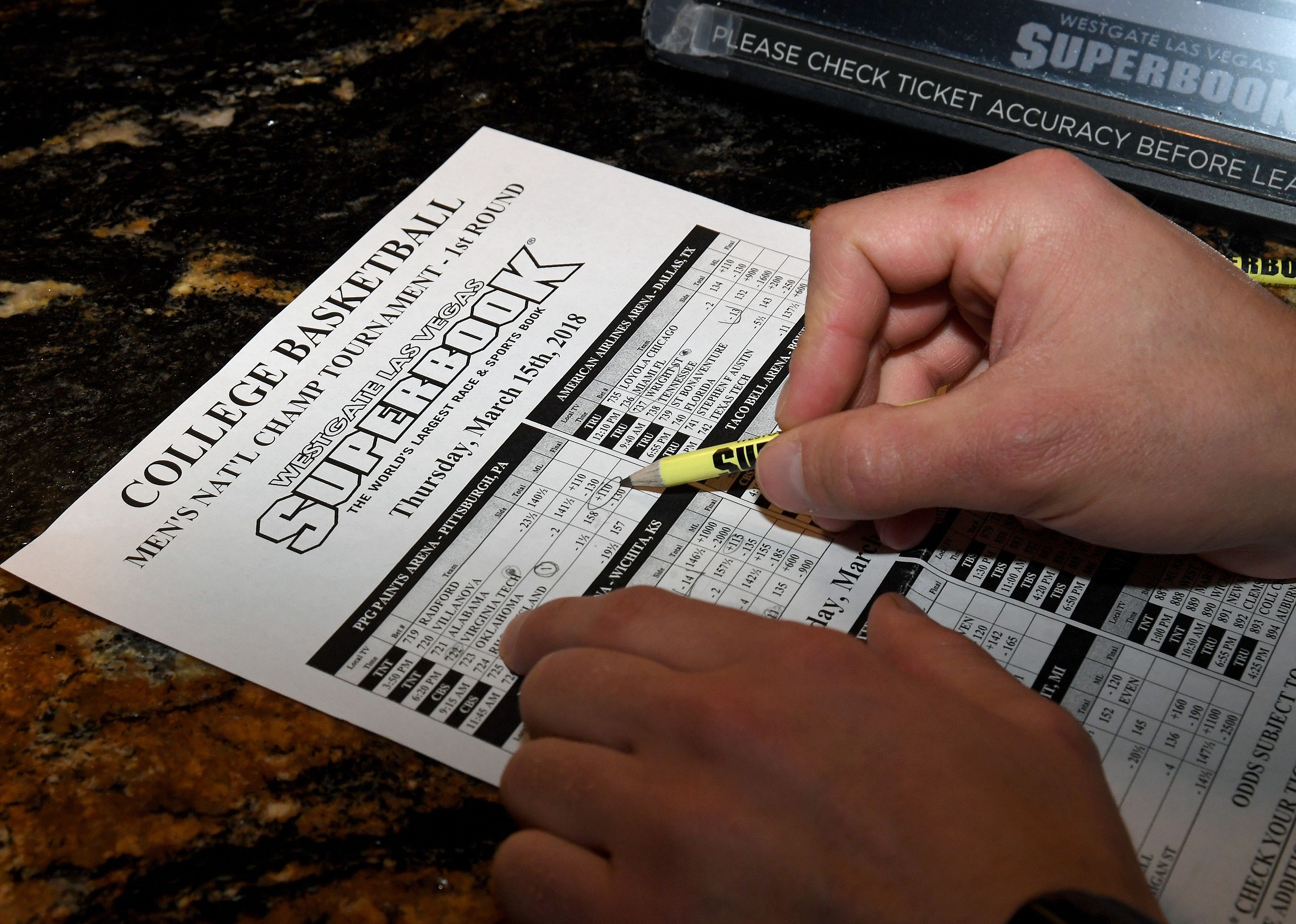Man makes bets during a viewing party for March Madness