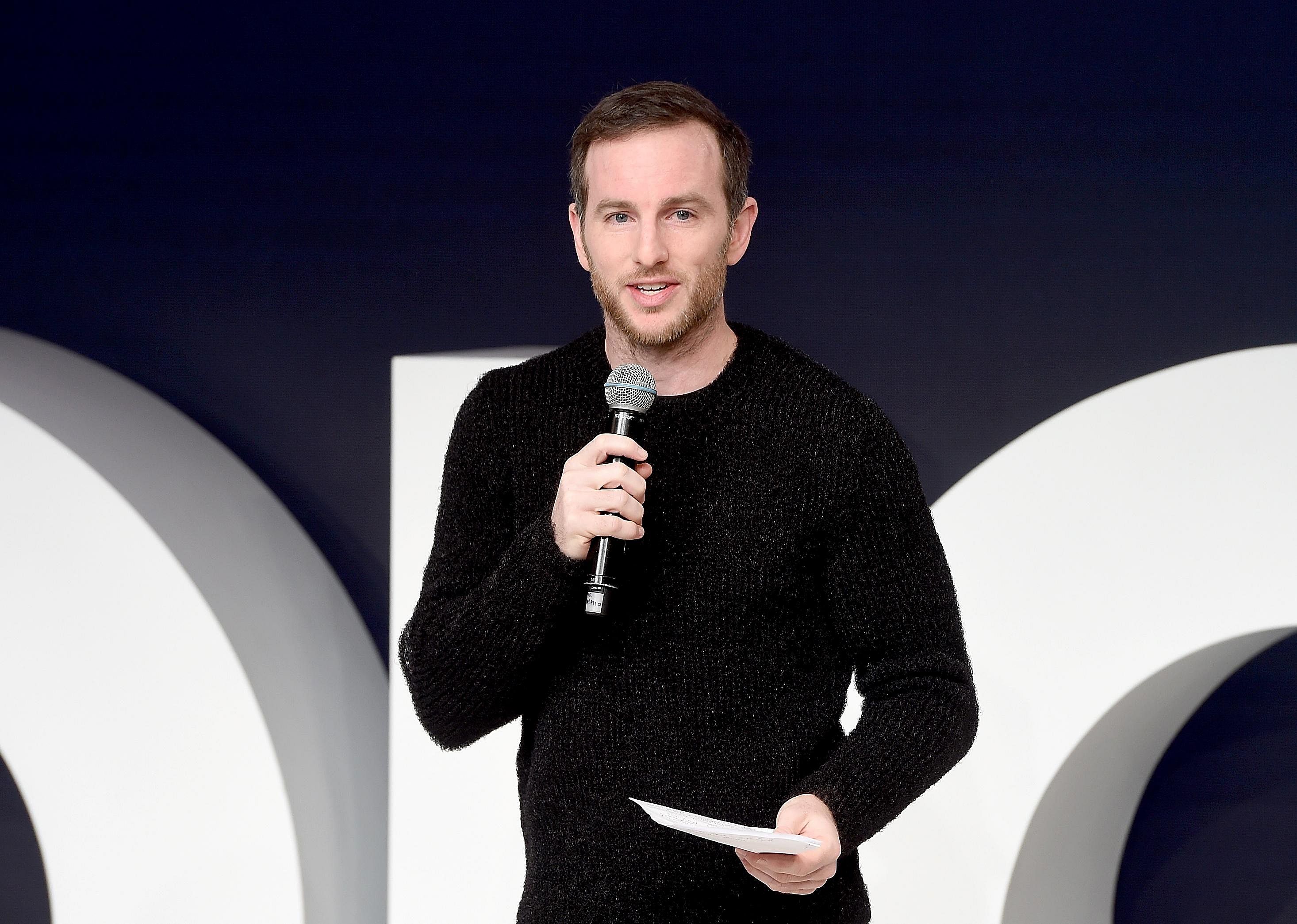 Joe Gebbia in a black sweater with a microphone on stage.