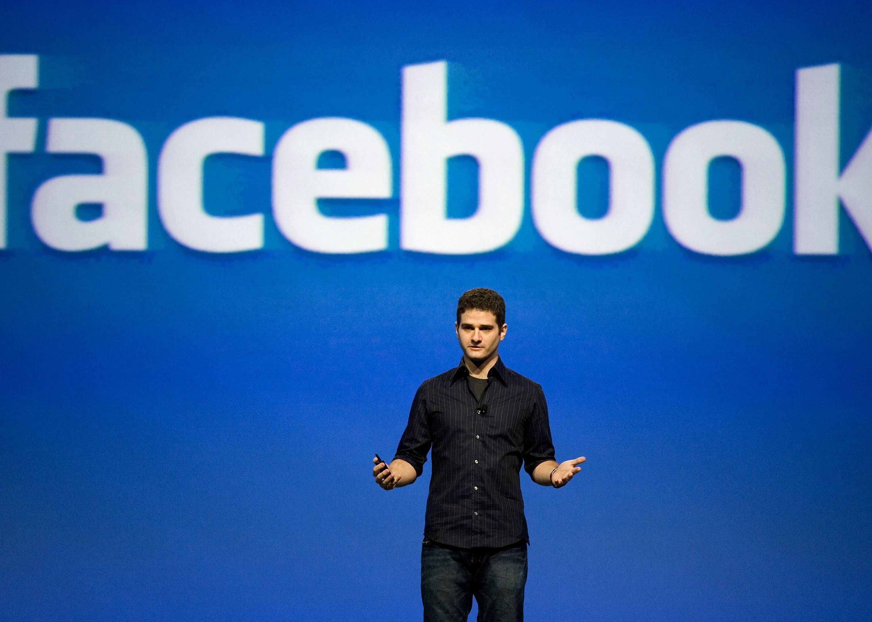 Dustin Moskovitz in front of a blue Facebook background on stage.
