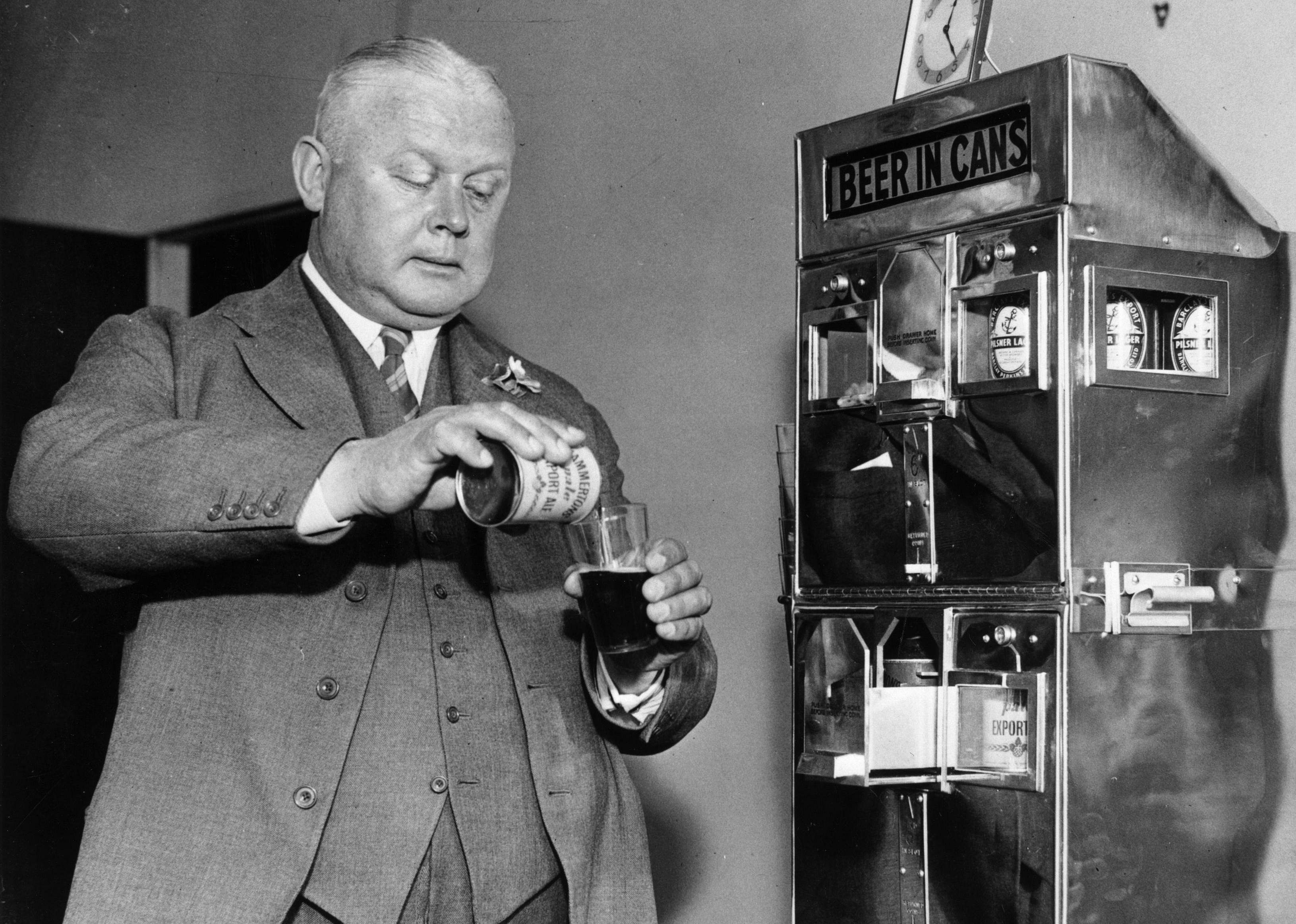 A man pours beer from a can in front of a dispenser with a Beer in Cans sign.