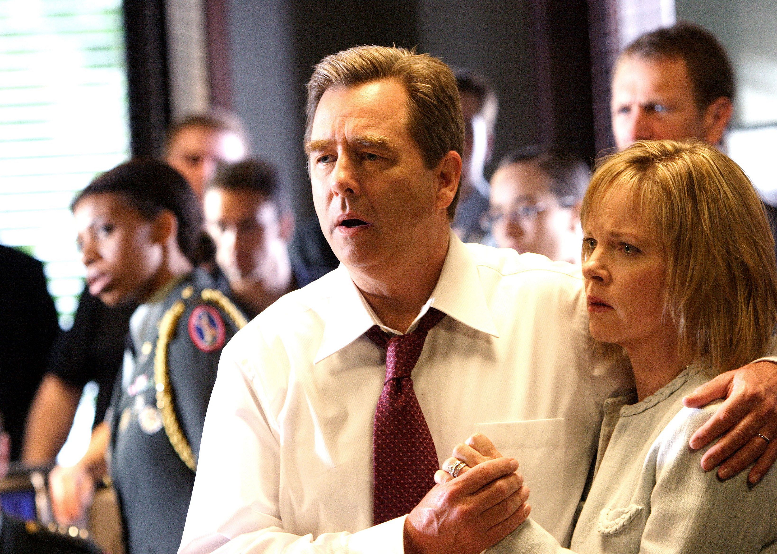 A man and woman hold onto each other while listening to someone talk.