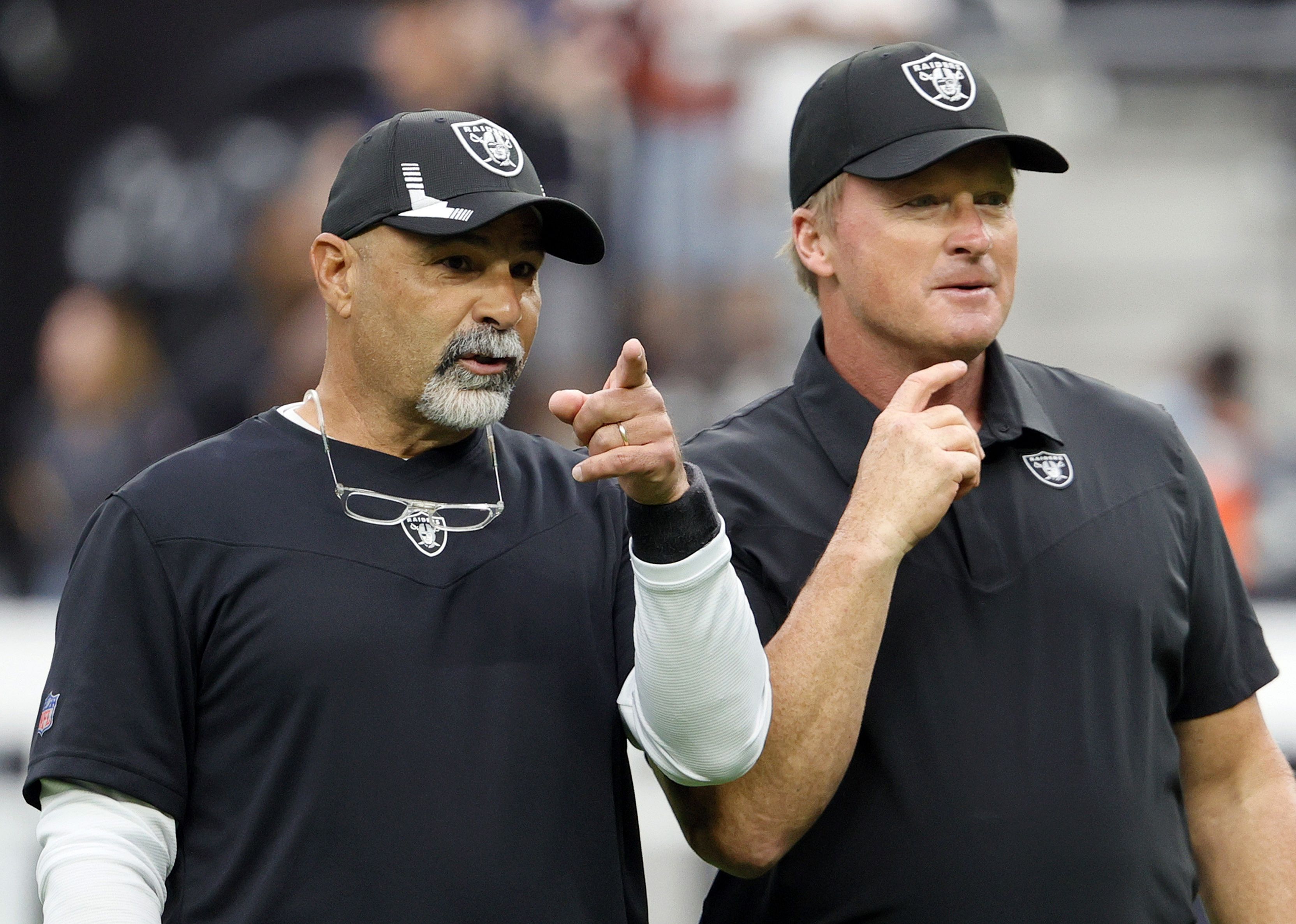 Assistant head coach Rich Bisaccia and head coach Jon Gruden of the Las Vegas Raiders talk on the field