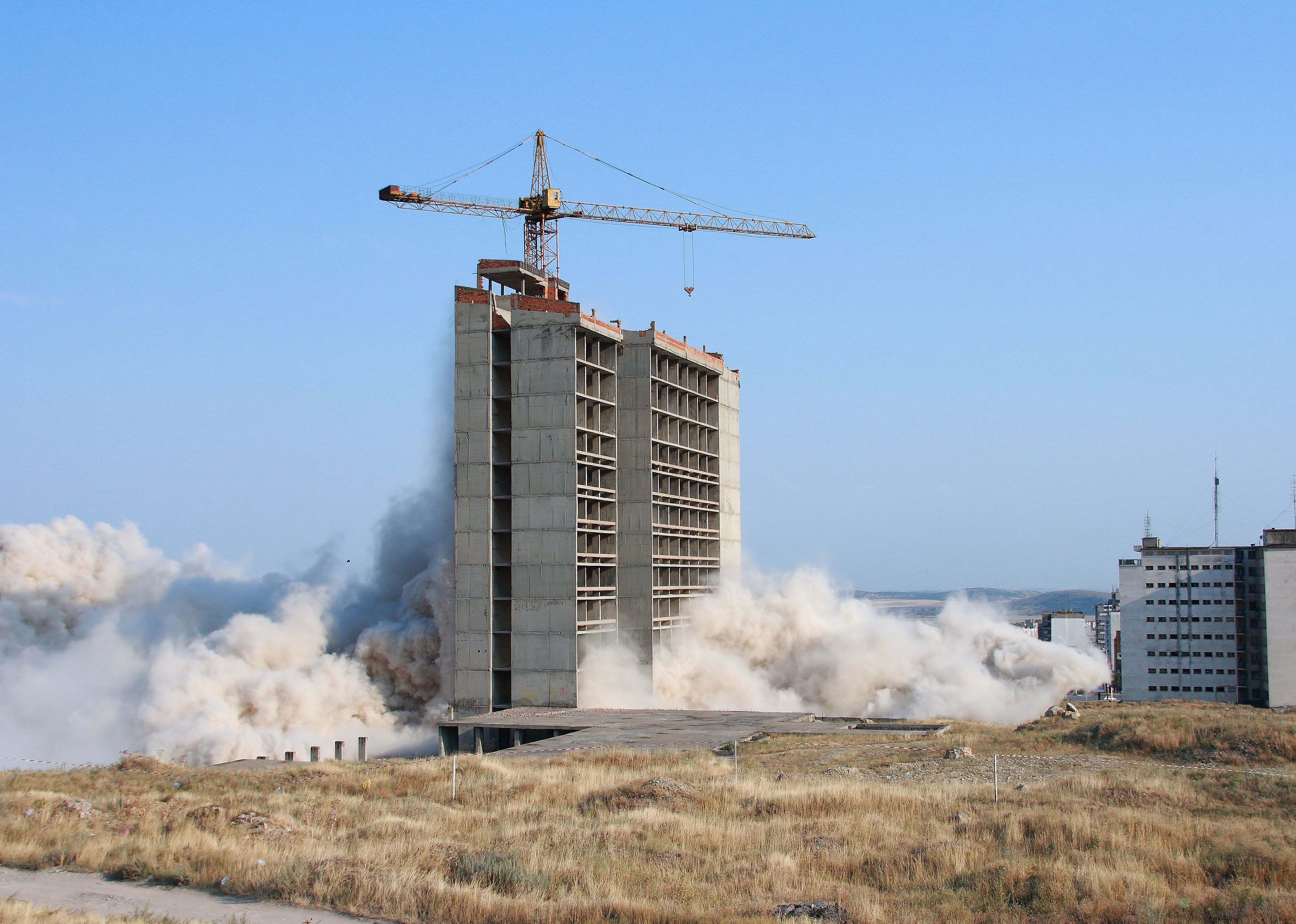 Part of a building is imploded by explosives.