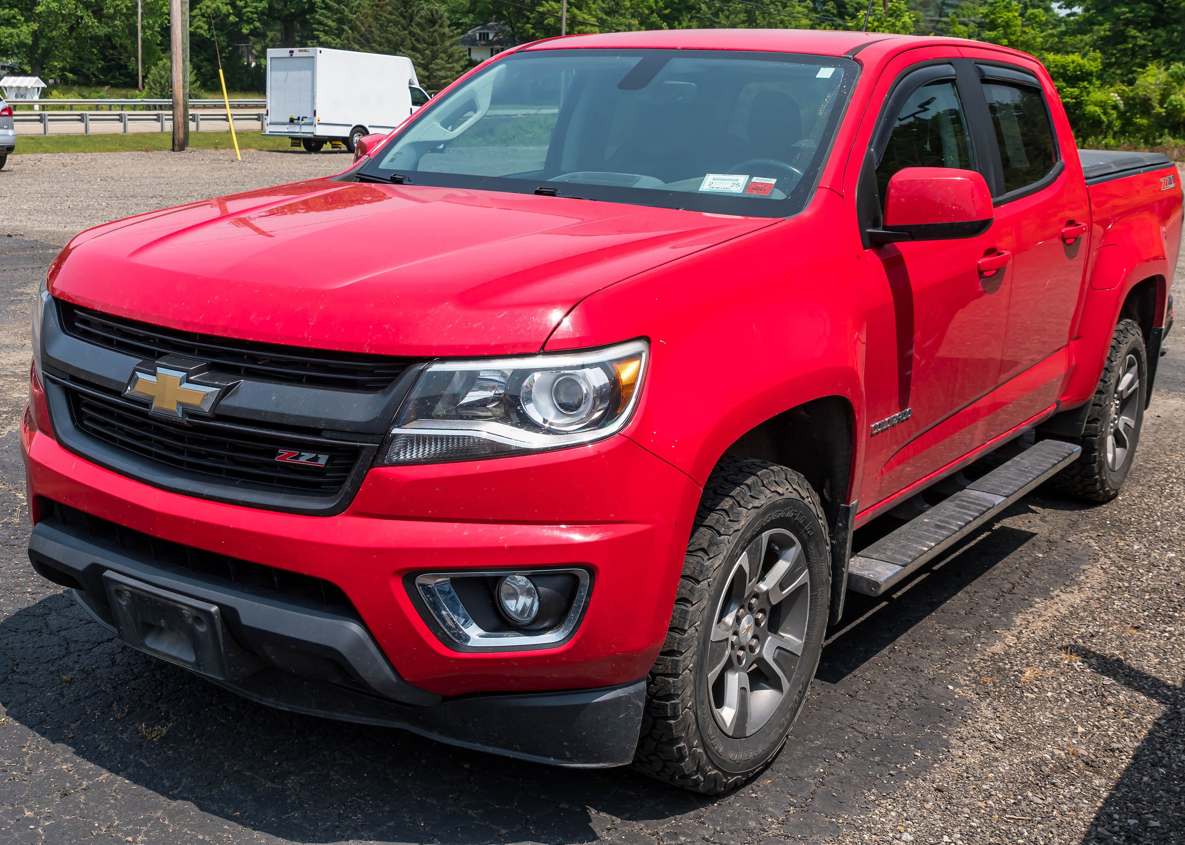 A red Chevrolet Colorado four door pick up for sale at a dealership.