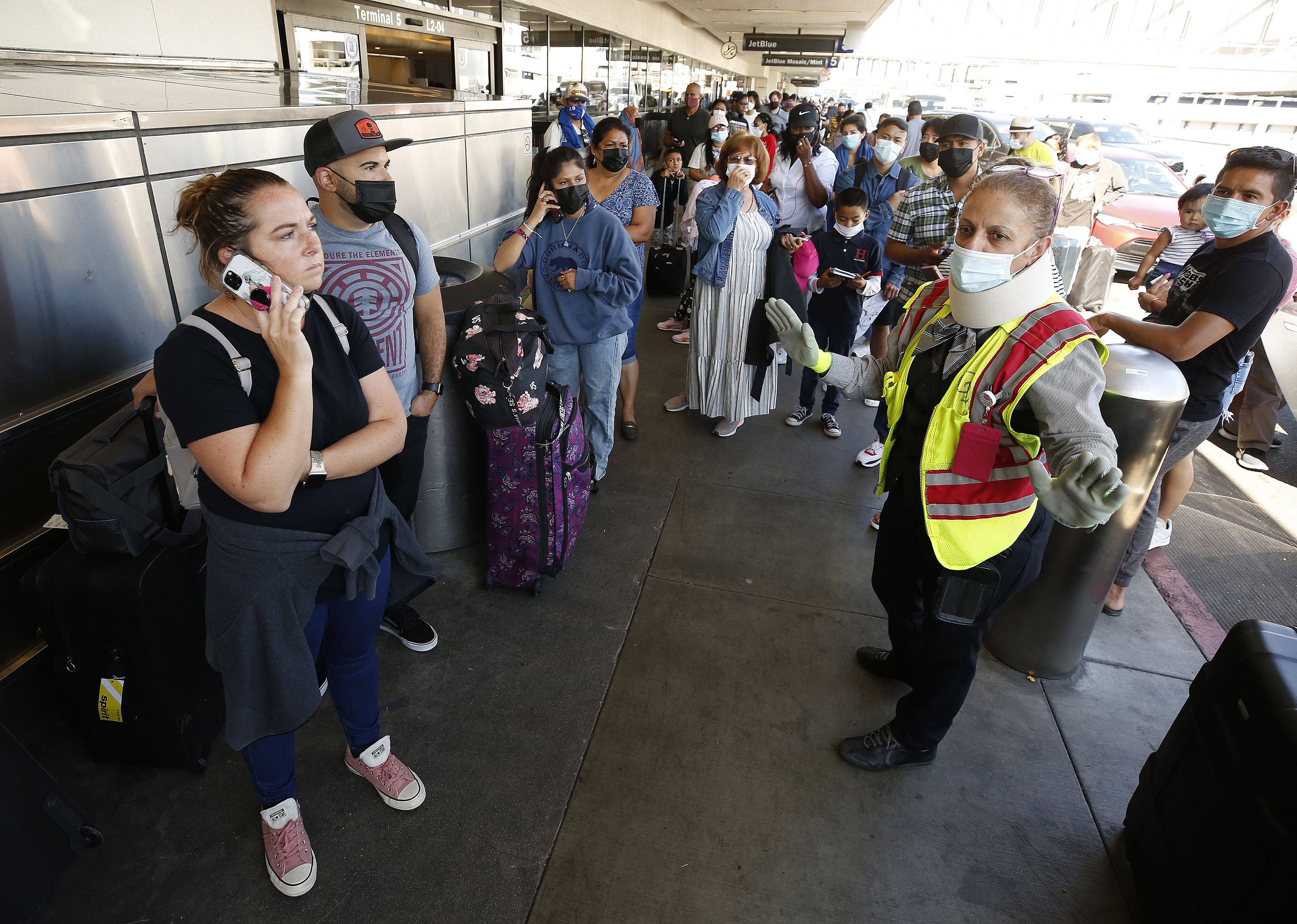 Frustrated Spirit Airlines customers wait in line outside after flights are cancelled.