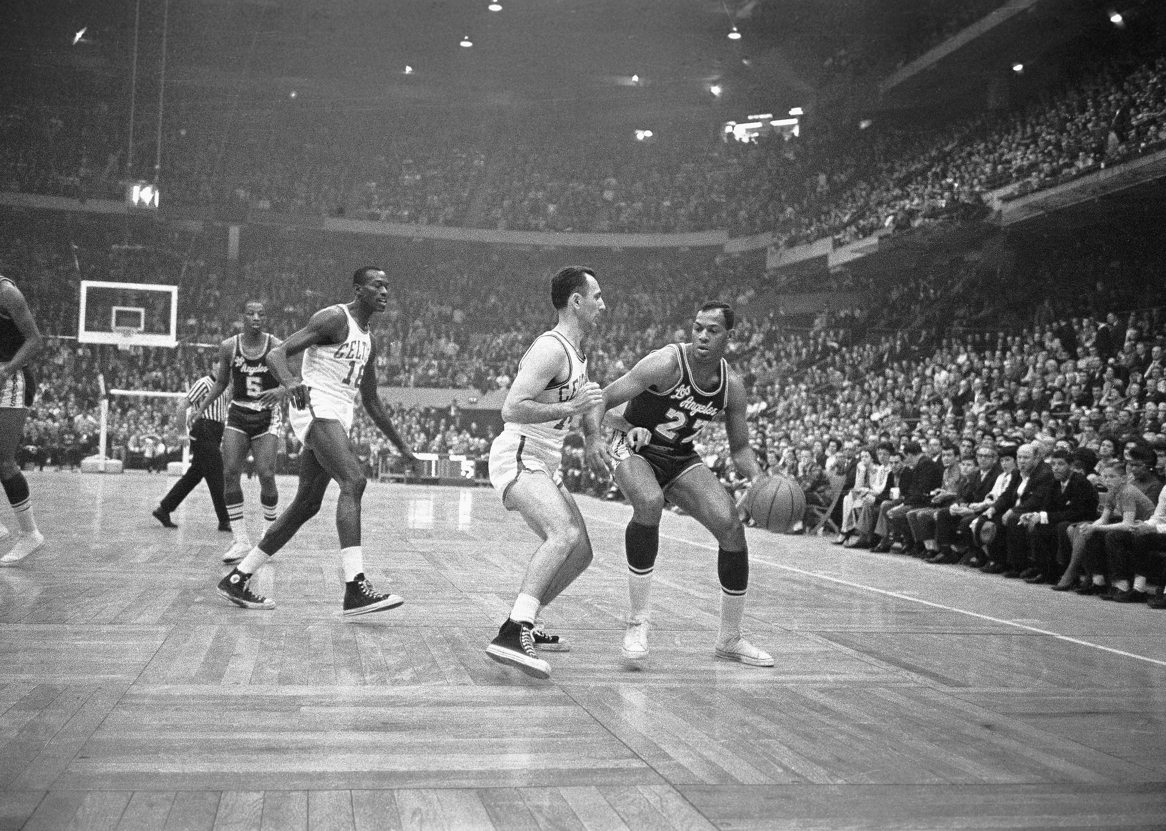 Elgin Baylor tries to maneuver the ball around Bob Cousy of the Boston Celtics