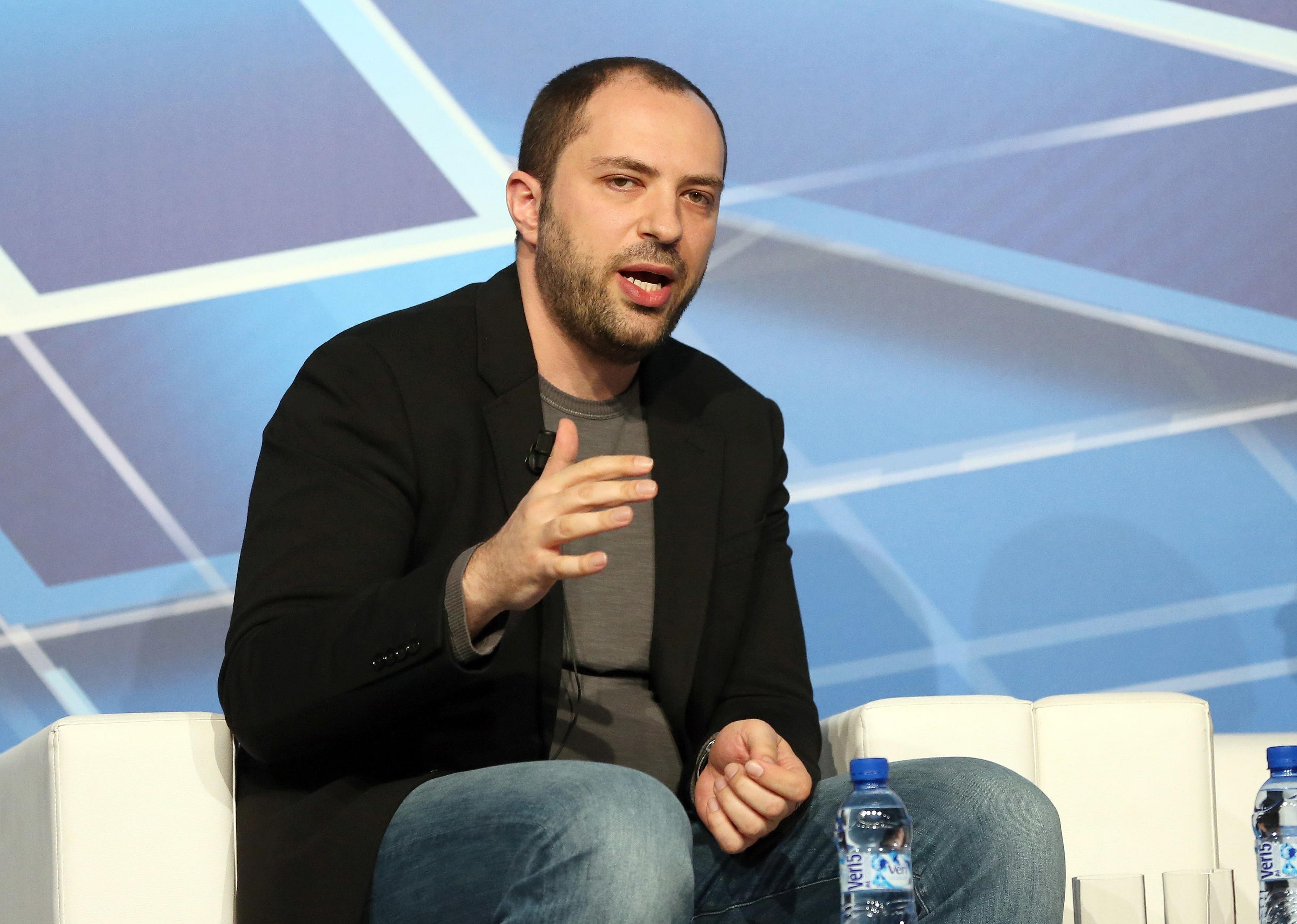 Jan Koum sitting on a white chair onstage.
