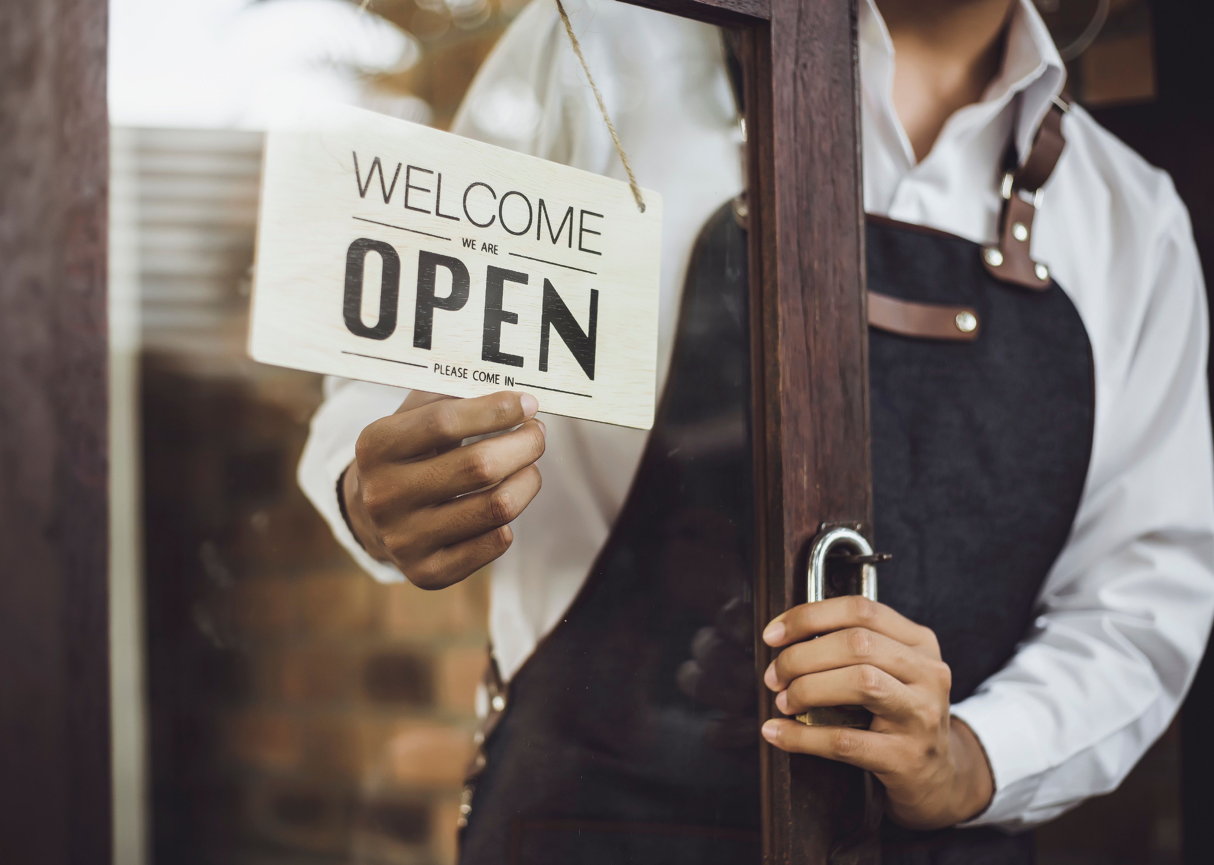 Store owner turning open sign through the door glass.