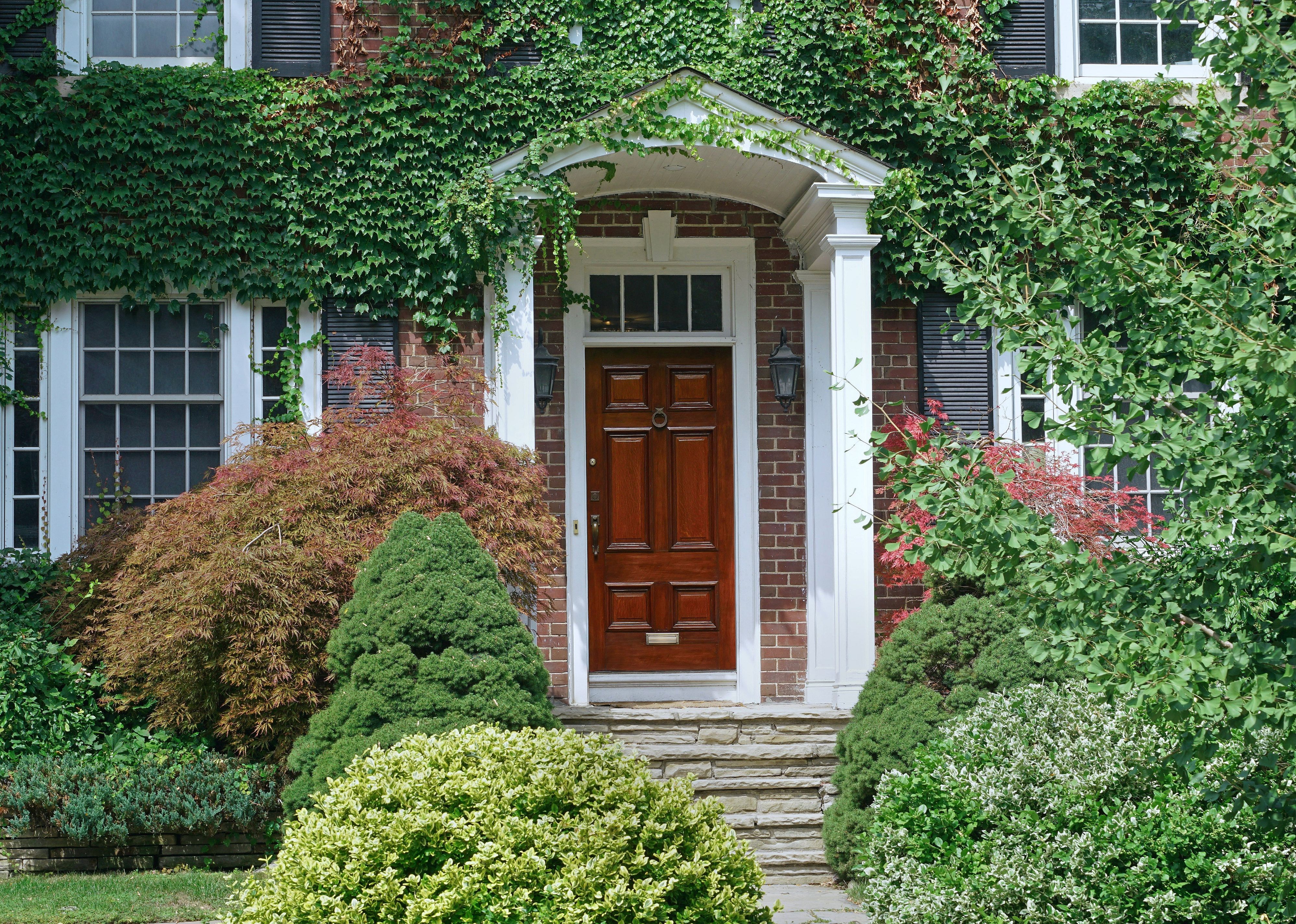 A brick house covered in greenery.