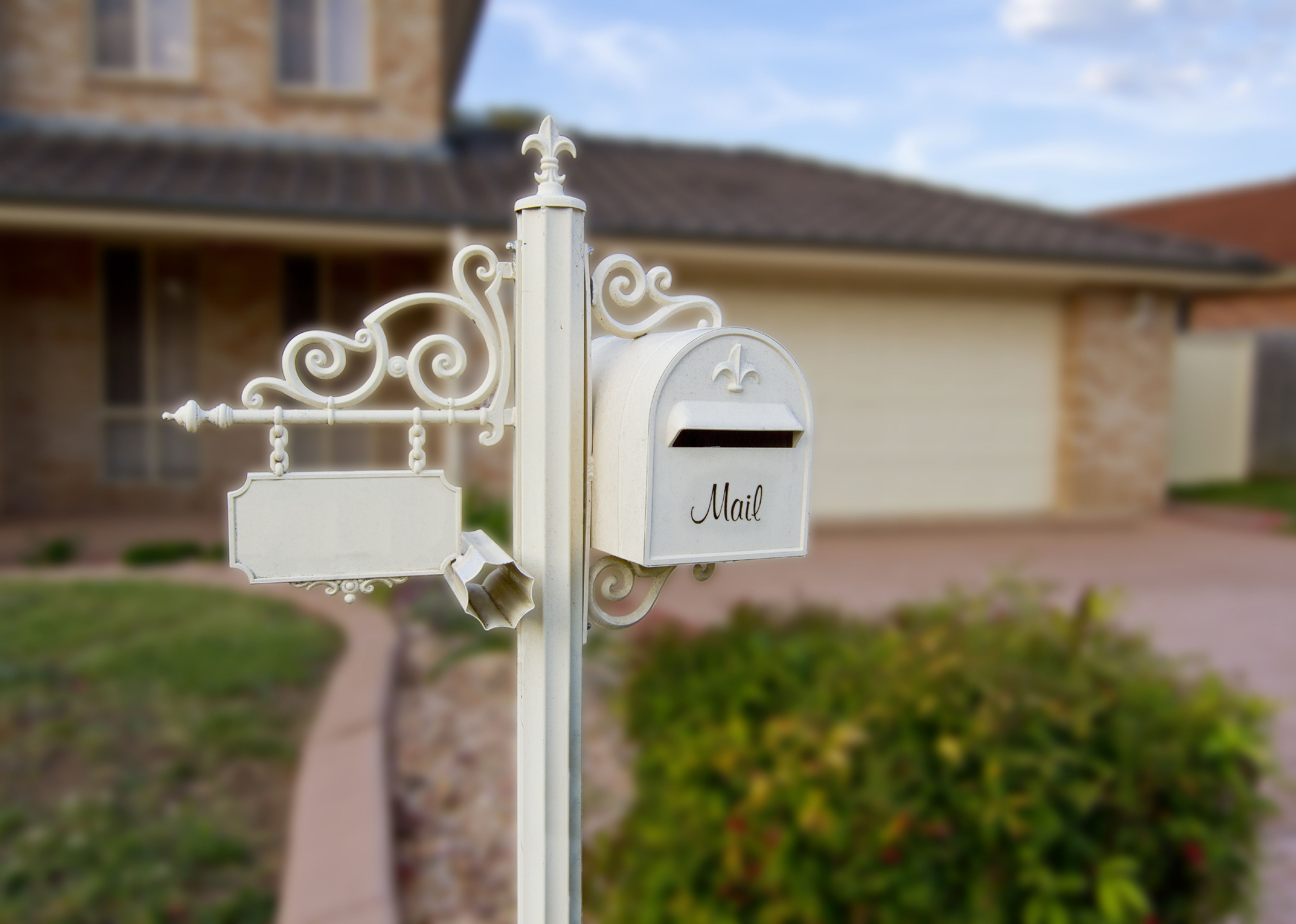 A white ornate mailbox in front of a home.