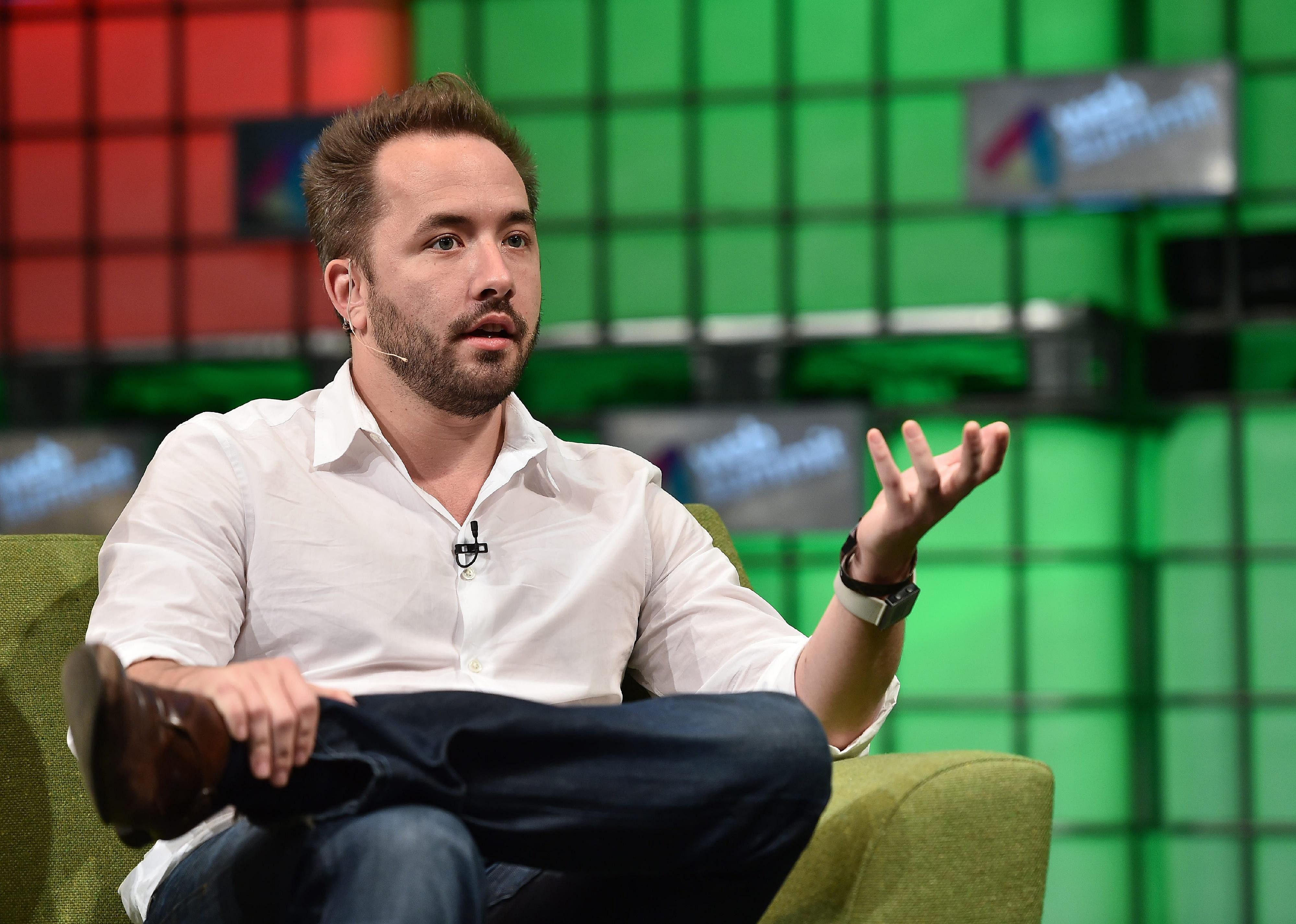Drew Houston in a white button down shirt in a chair onstage.