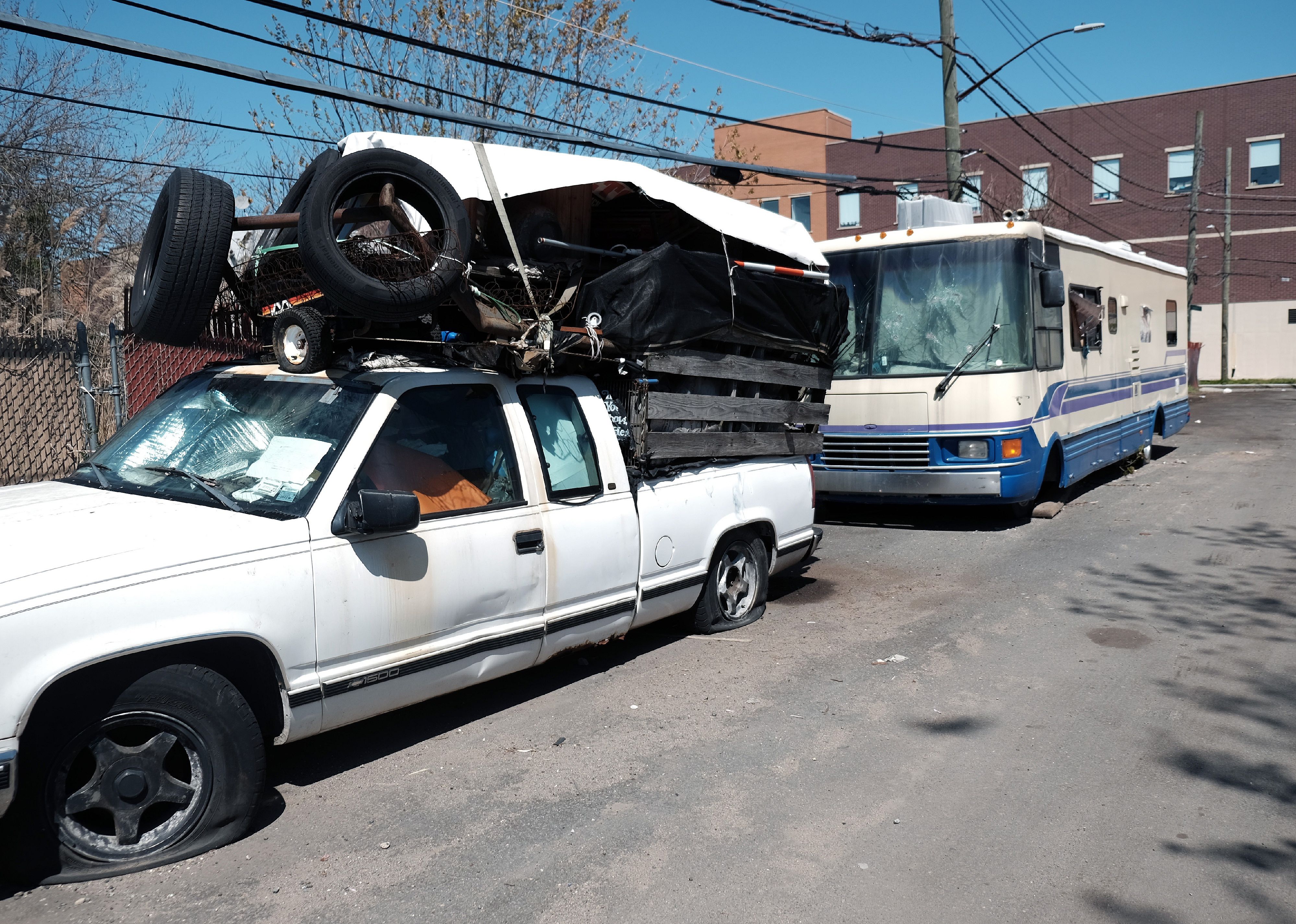 An abandoned truck and motorhome sit on the side of the road.