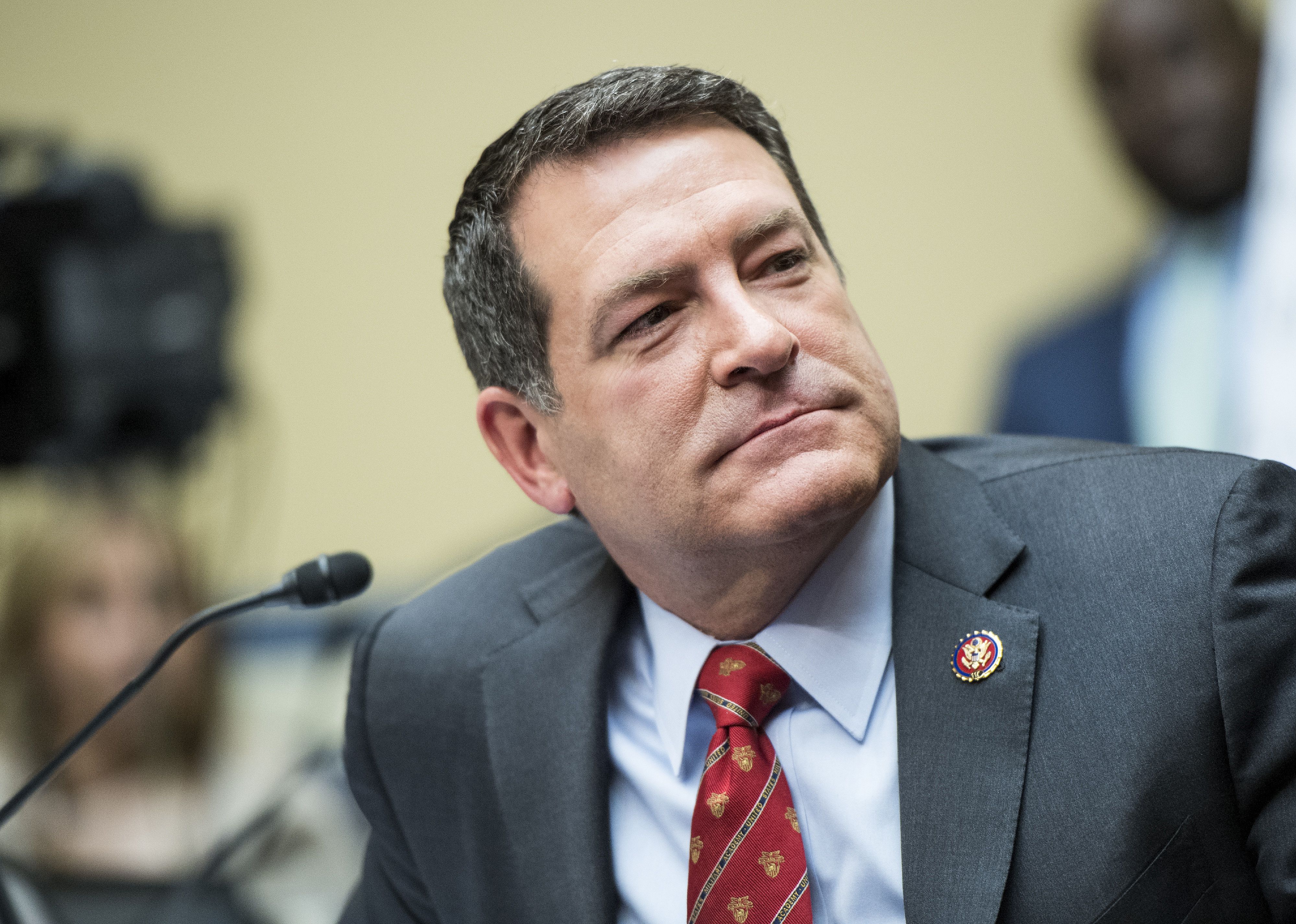 Mark Green in a gray suit with a red tie in front of a microphone.