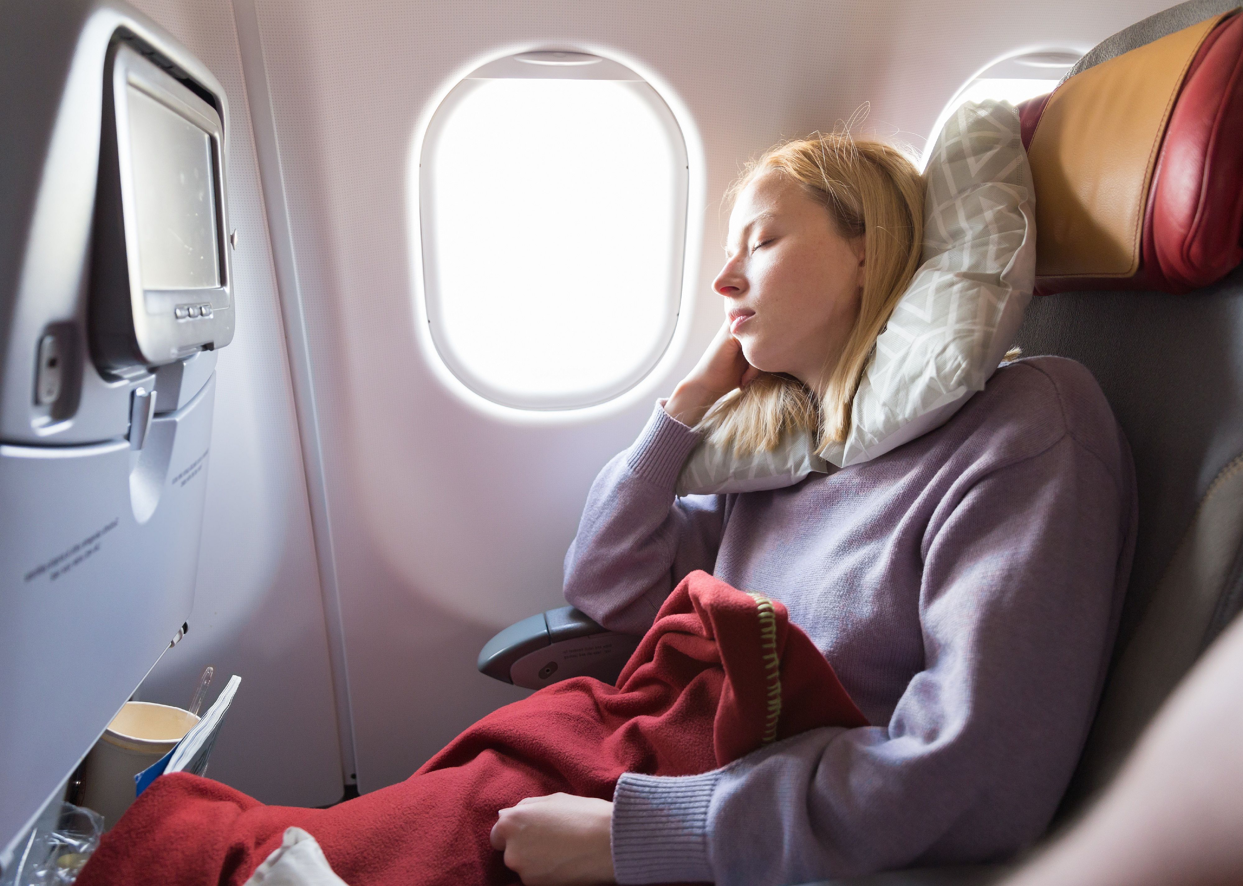 Woman sleeping while traveling by airplane on long distance flight.