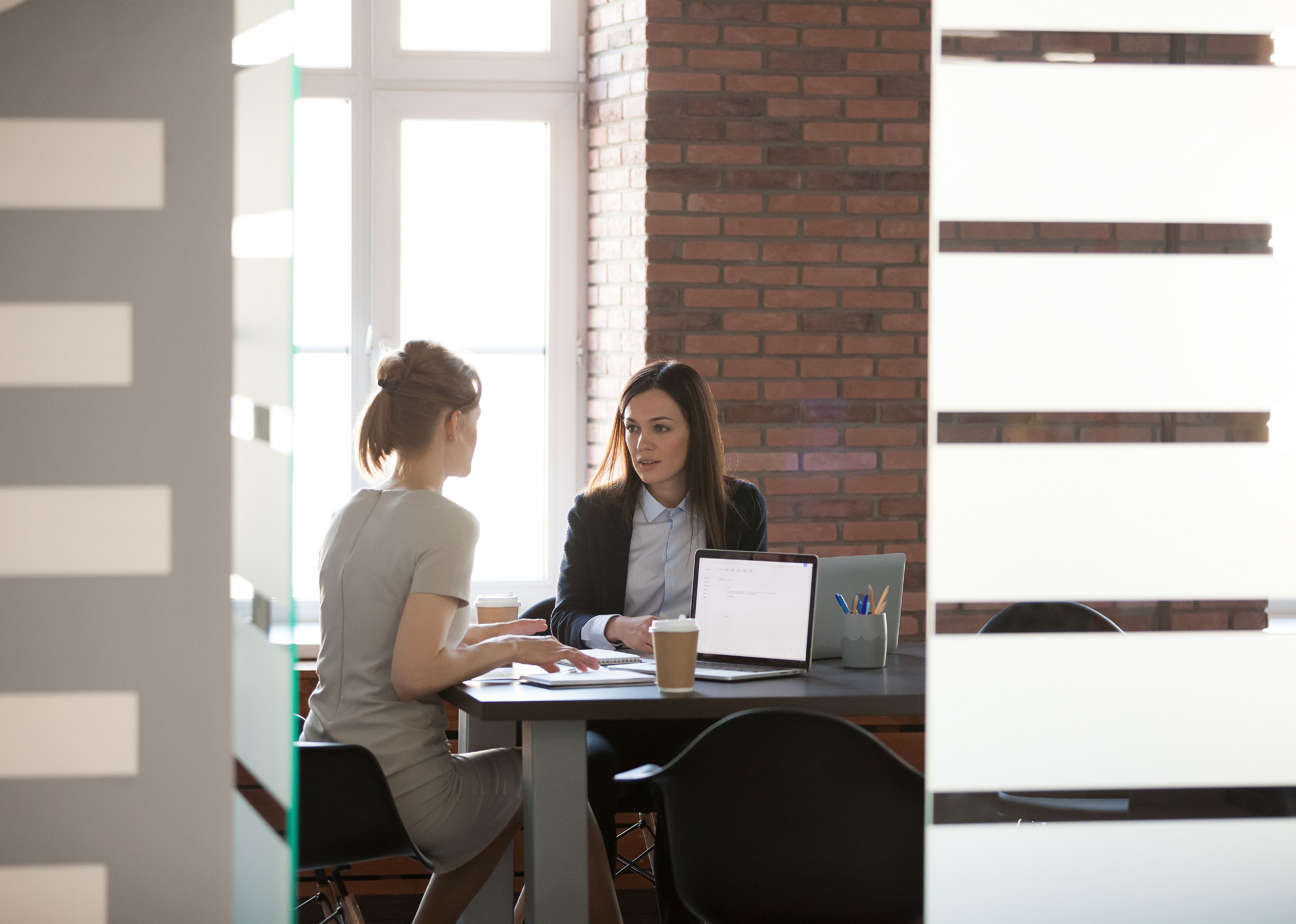 Two businesswomen speaking at a table